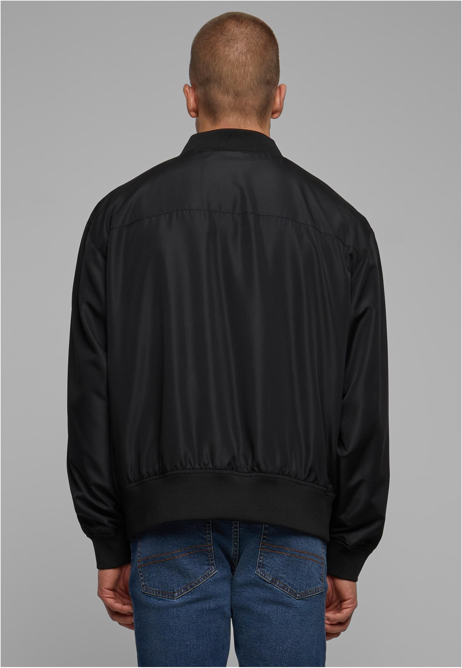 Baksidan av en man som bär en svart UC Recycled Bomber Jacket.