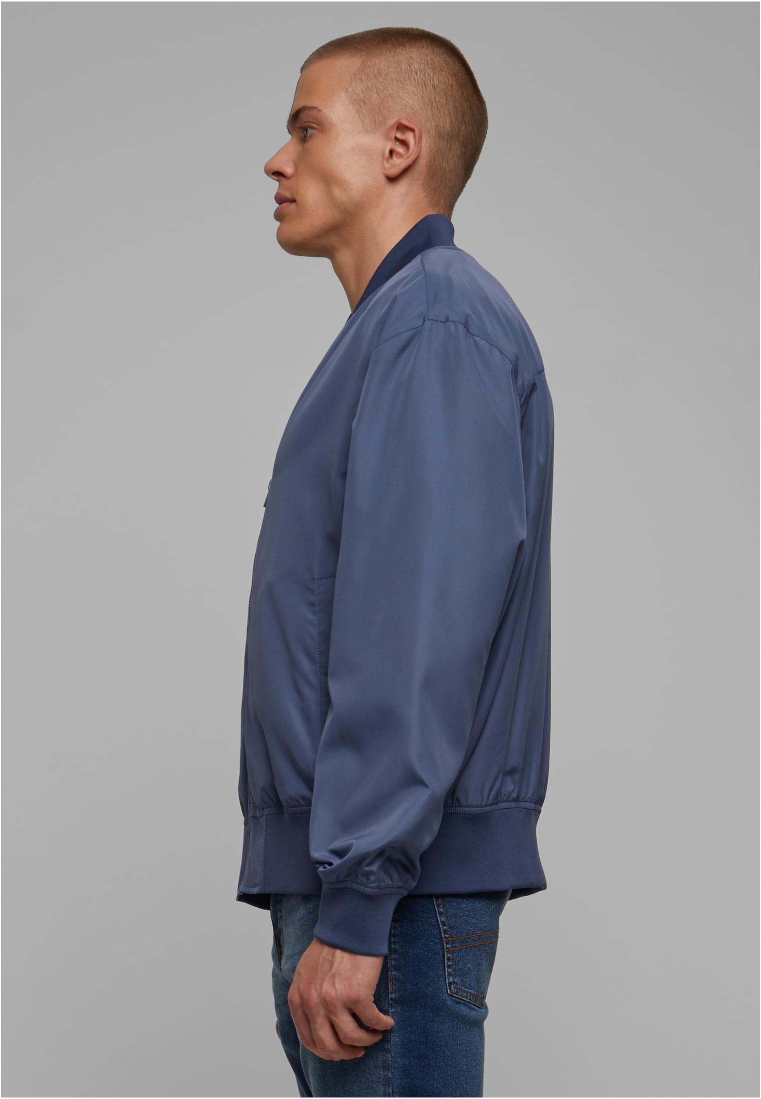 Sidovy av en man som bär en blå UC Recycled Bomber Jacket.