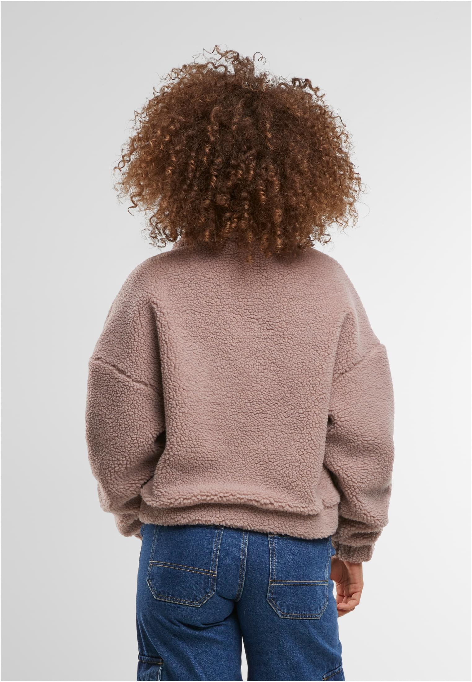 Kvinna med lockigt hår, sedd bakifrån, som bär en rosa UC Short Sherpa Button Jacket.