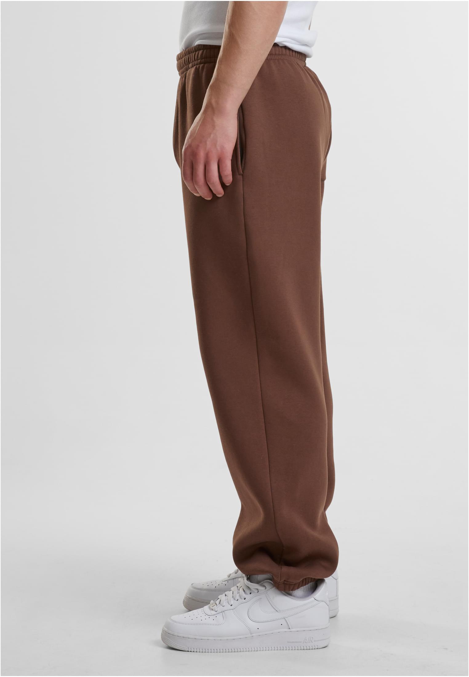 Sidovy av en man som bär bruna Fluffy Sweatpants och vita sneakers.