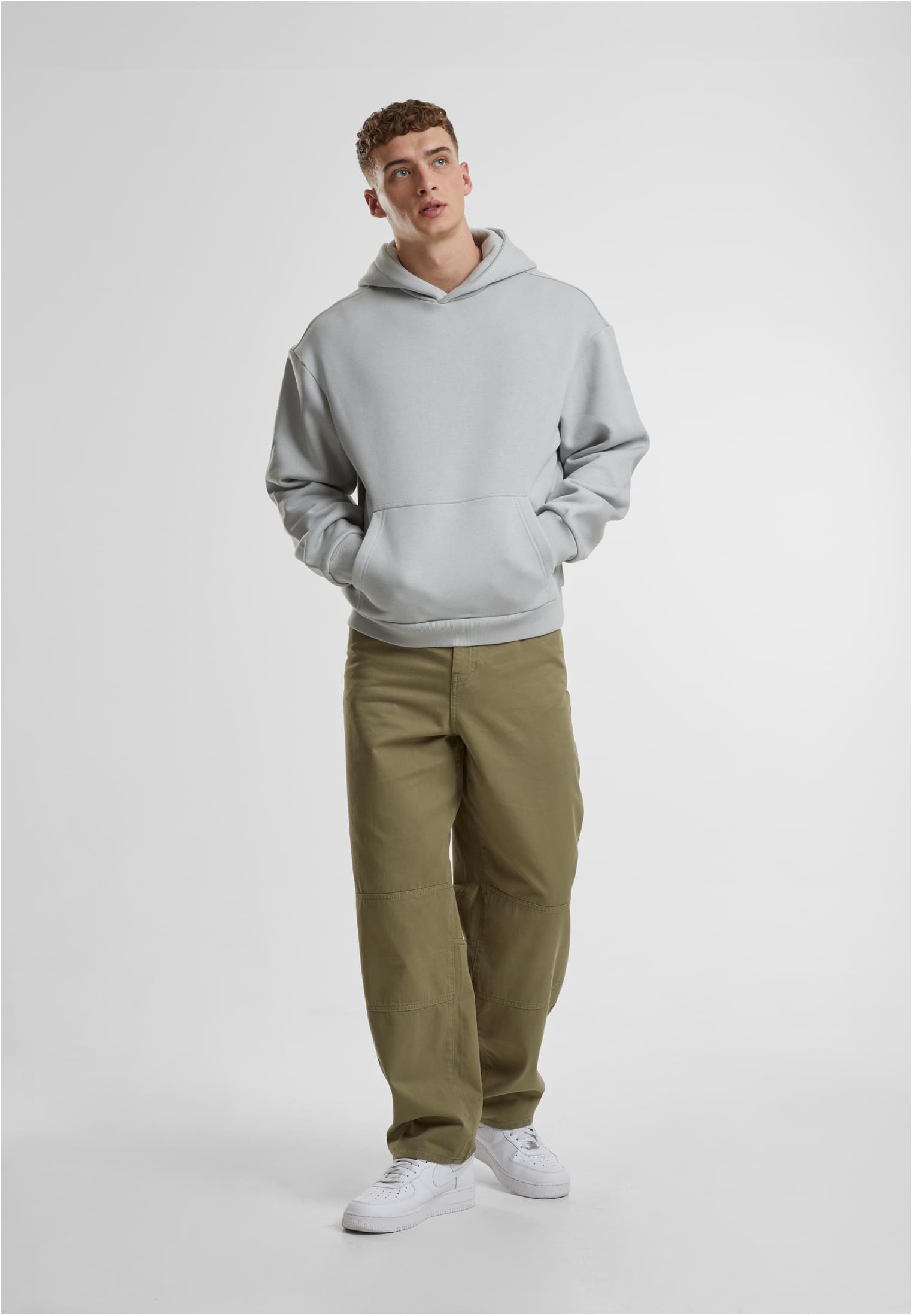 Helkroppsbild av en man som bär en ljuslila Fluffy Hoody, gröna byxor och vita sneakers mot en vit bakgrund.