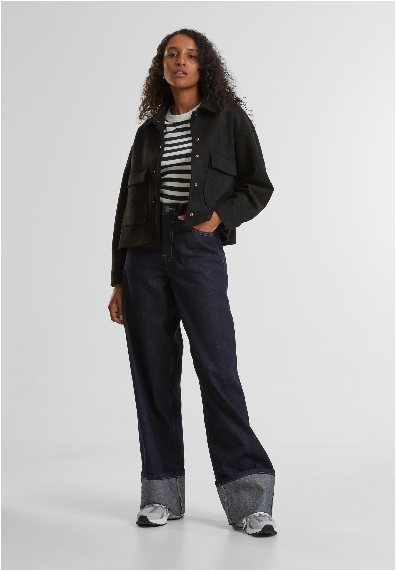 En kvinna som bär den svarta UC Soft Touch Jacket, stylad med en randig tröja och mörka jeans.