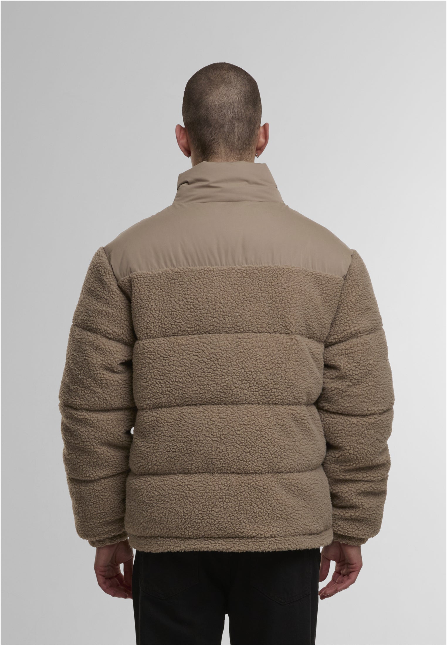 En man visar baksidan av en beige UC Fabric Mix Teddy Puffer Jacket.