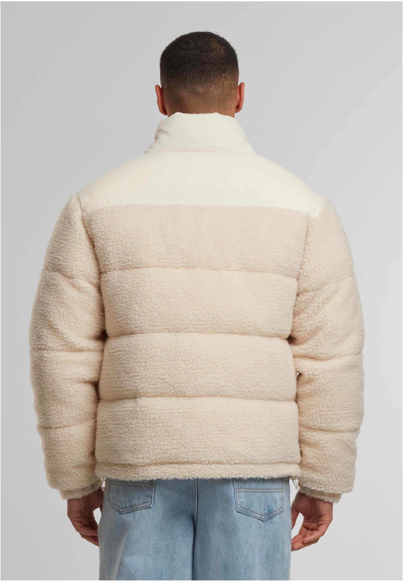 Baksidan av en man som bär en beige teddy-pufferjacka med en vit panel över axlarna.