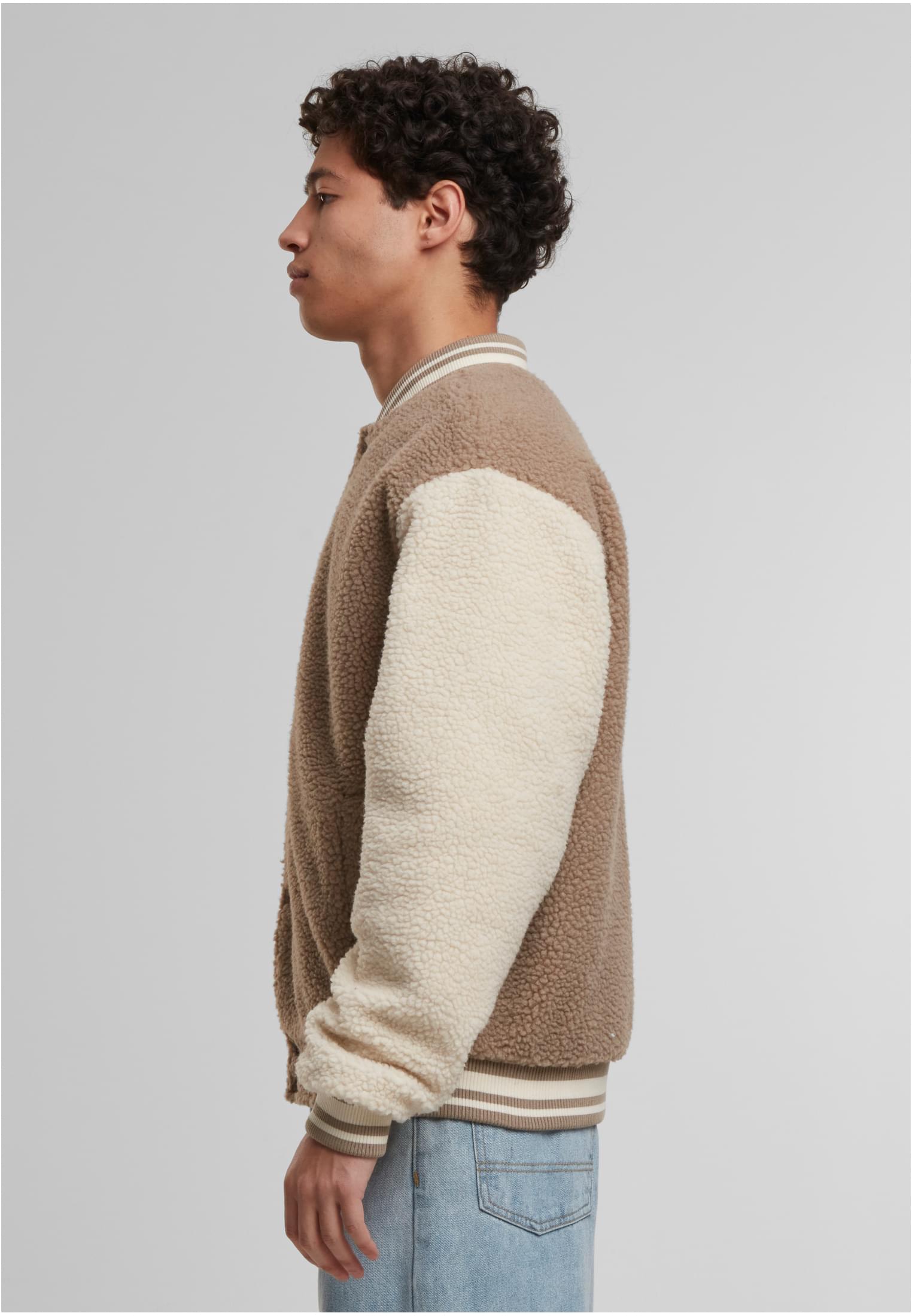 Sidovy av en man som bär en mörk taupefärgad Teddy College Jacket med benvita ärmar.