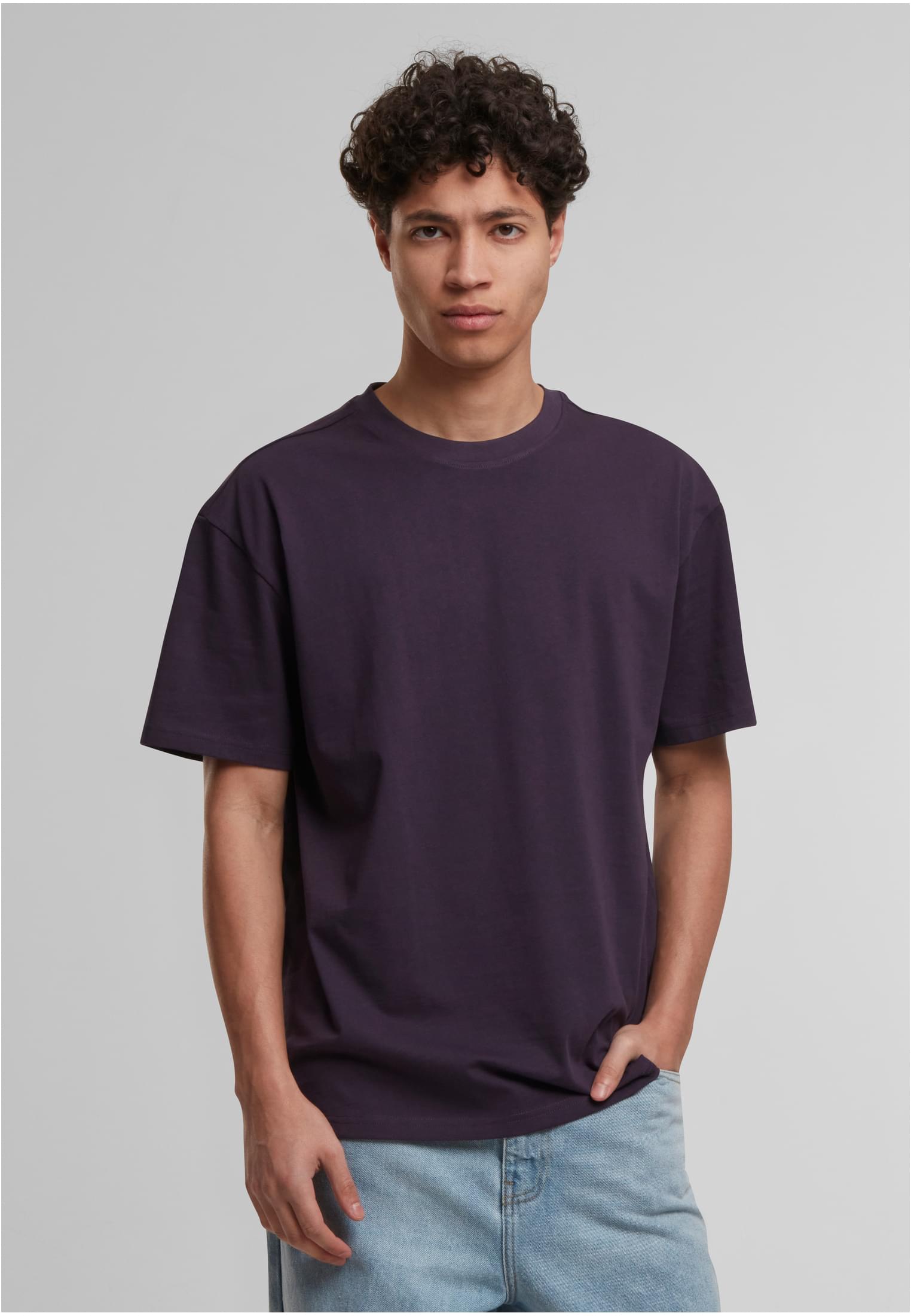 Manlig modell som bär en mörklila Cotton Loose Tee t-shirt och ljusa jeans.