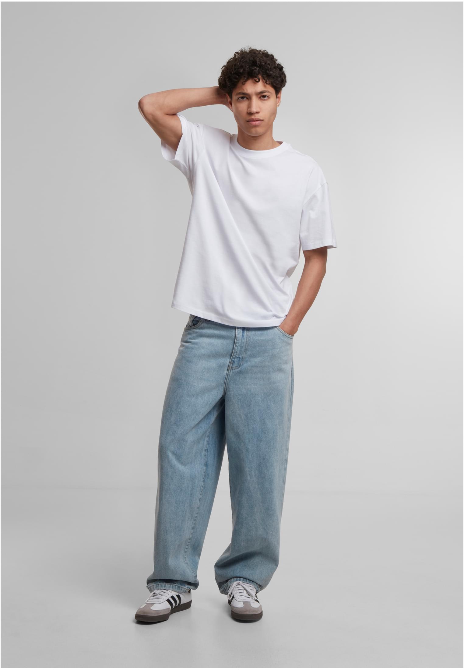 En manlig modell poserar i en vit löst sittande t-shirt och ljusblå baggy jeans.