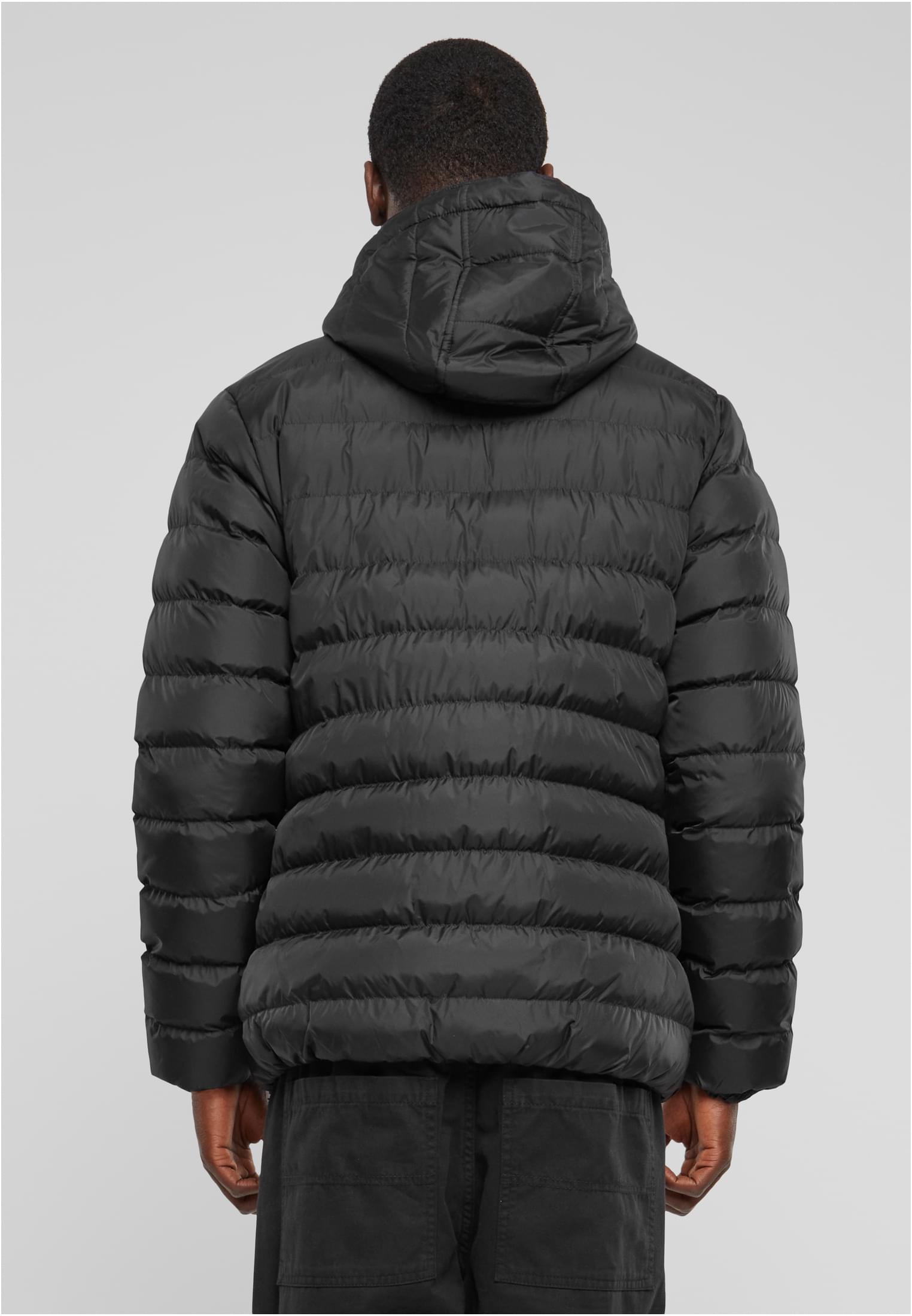 En man visar baksidan av en svart, quiltad UC Basic Bubble Jacket med huva.