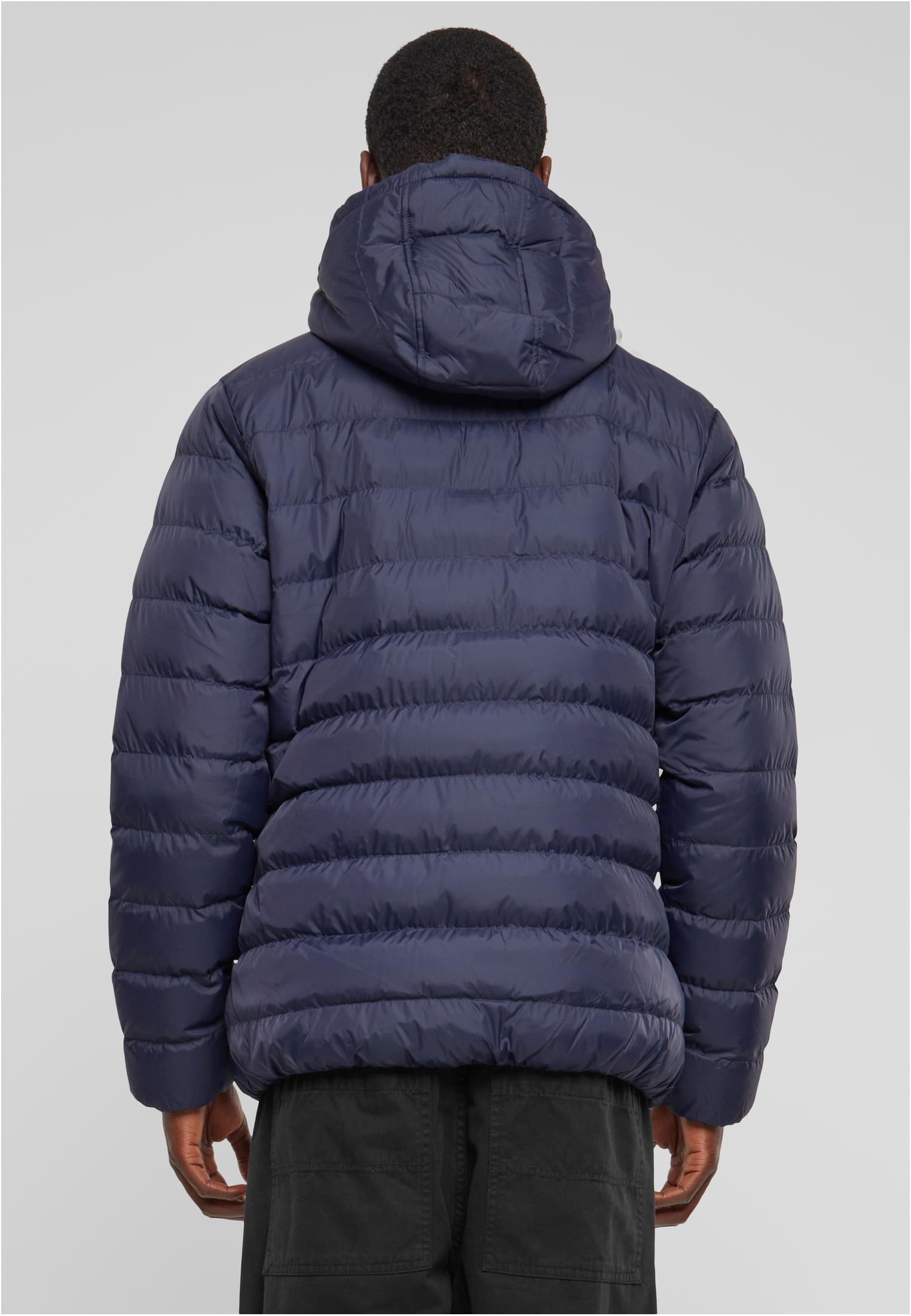 Baksidan av en man som bär en mörkblå vadderad jacka med huva.
