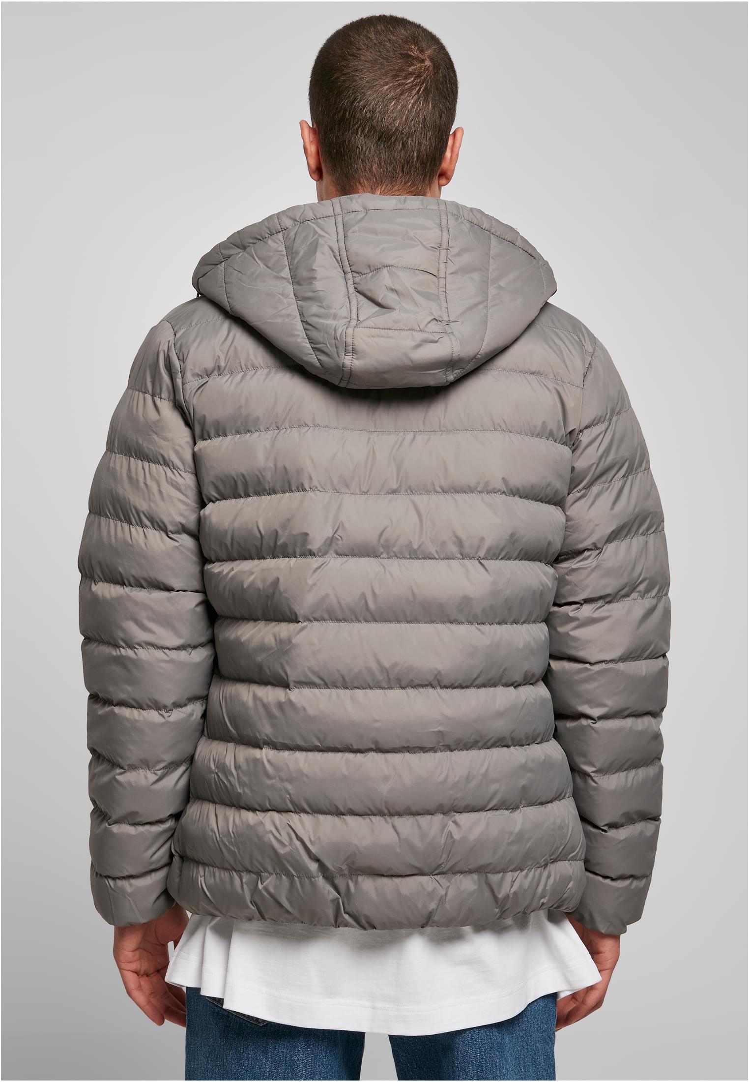 En man visar baksidan av en grå quiltad UC Basic Bubble Jacket med huva.