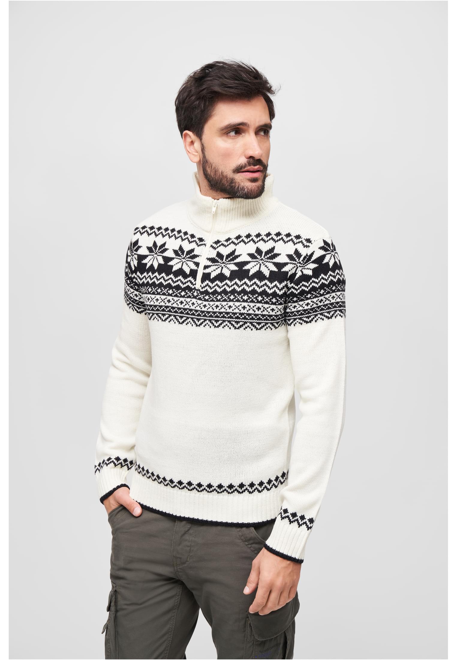 En man i en vit stickad tröja med ett svart norskt mönster och en krage med dragkedja.