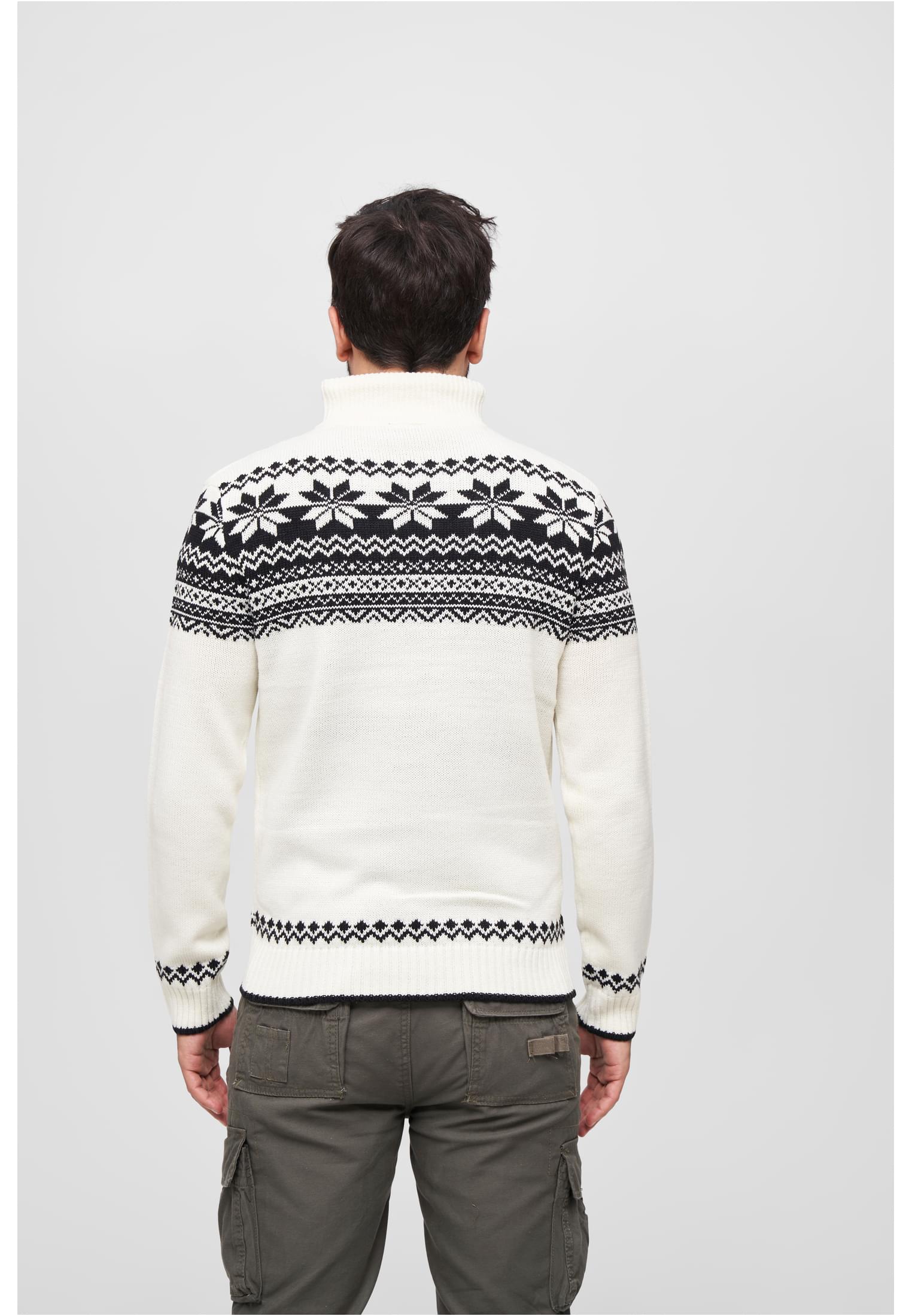 En man visar baksidan av en vit stickad tröja med ett klassiskt svart norskt mönster.