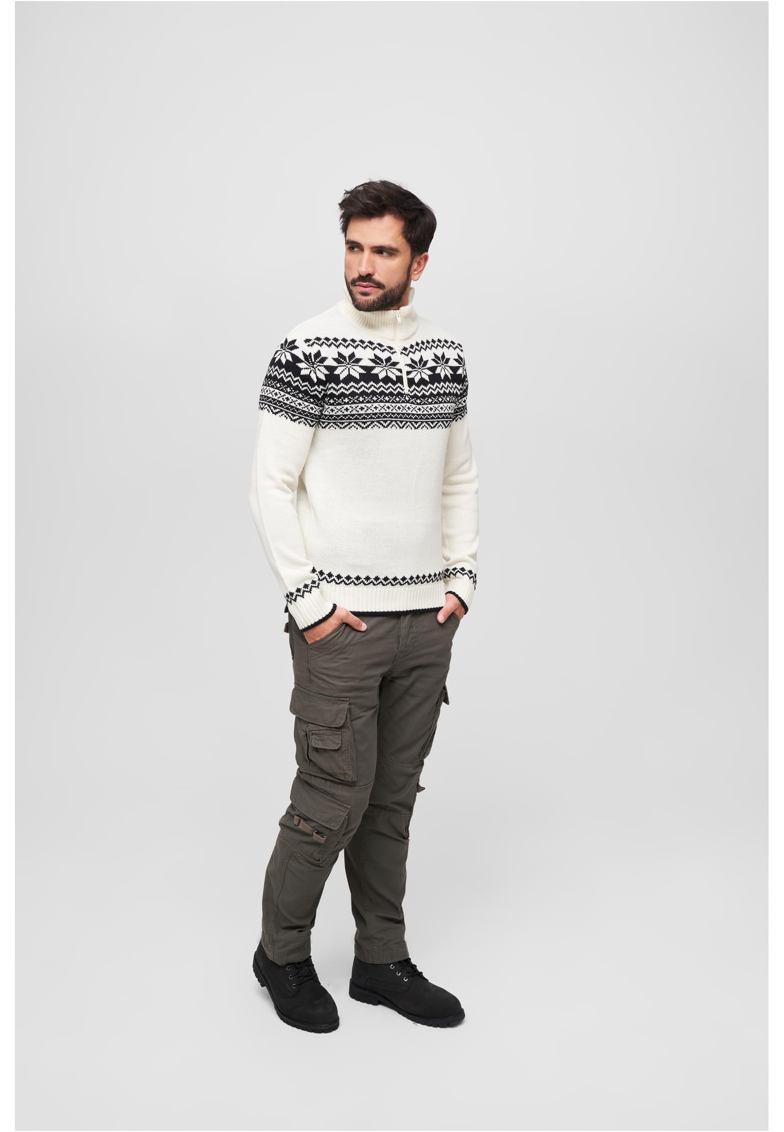 En man visar upp den vita stickade tröjan B Troyer Norweger med svart skandinaviskt mönster, stylad med gröna cargobyxor.