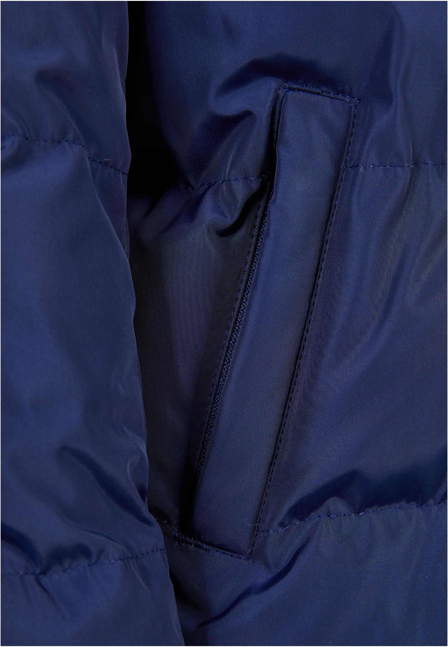 Detaljbild på en sidoficka med dragkedja på en mörkblå pufferjacka.