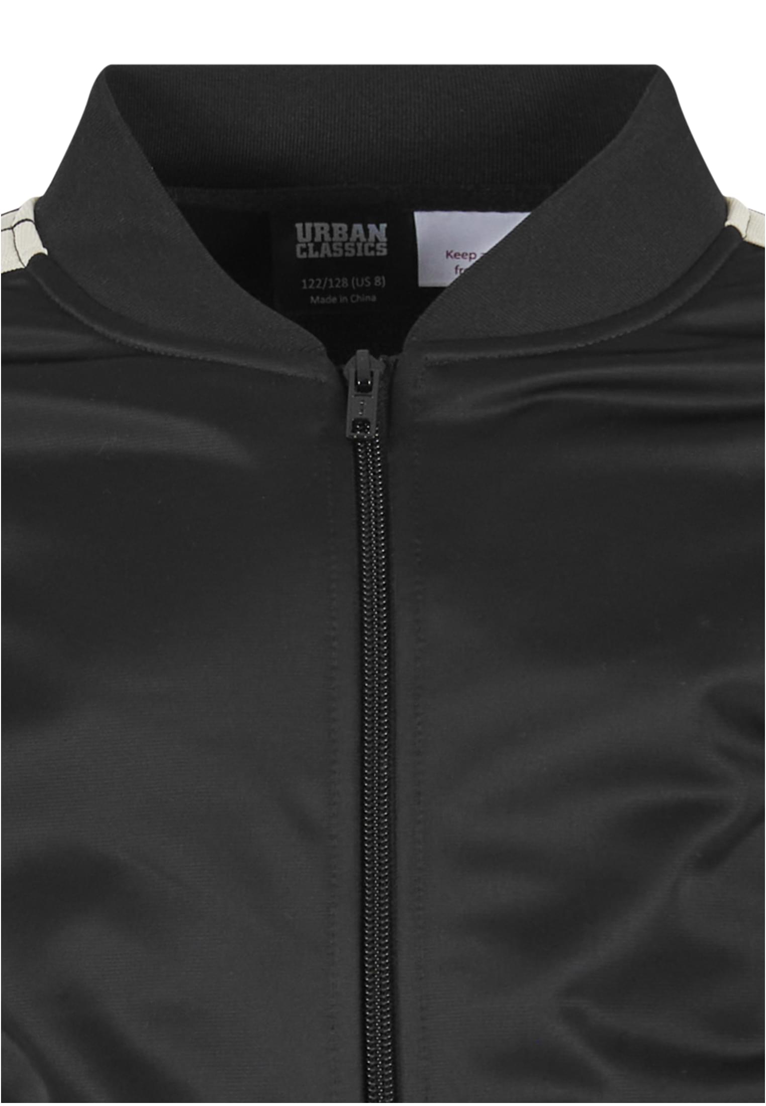 Närbild på den svarta UC Boys Tennis Core Jacket, som visar den ribbade kragen, dragkedjan fram och Urban Classics-märkesetiketten på insidan.