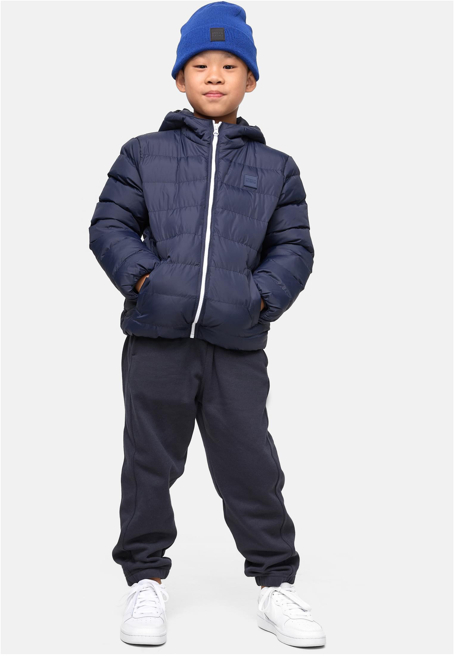 En pojke visar framsidan av sin marinblåa UC Boys Basic Bubble Jacket med händerna i fickorna.