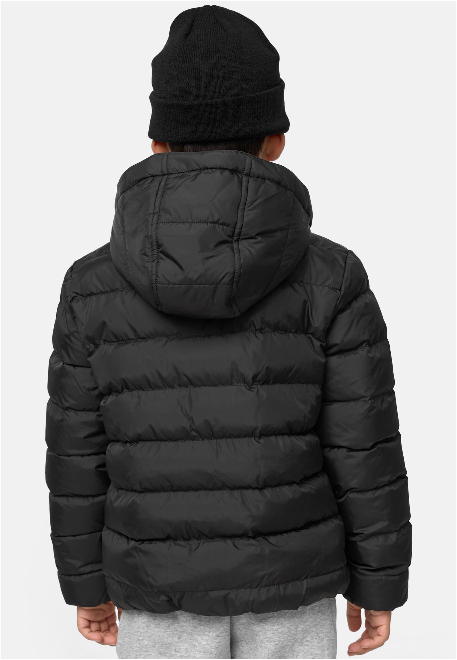 En pojke sedd bakifrån som bär en svart UC Boys Basic Bubble Jacket och en svart mössa.