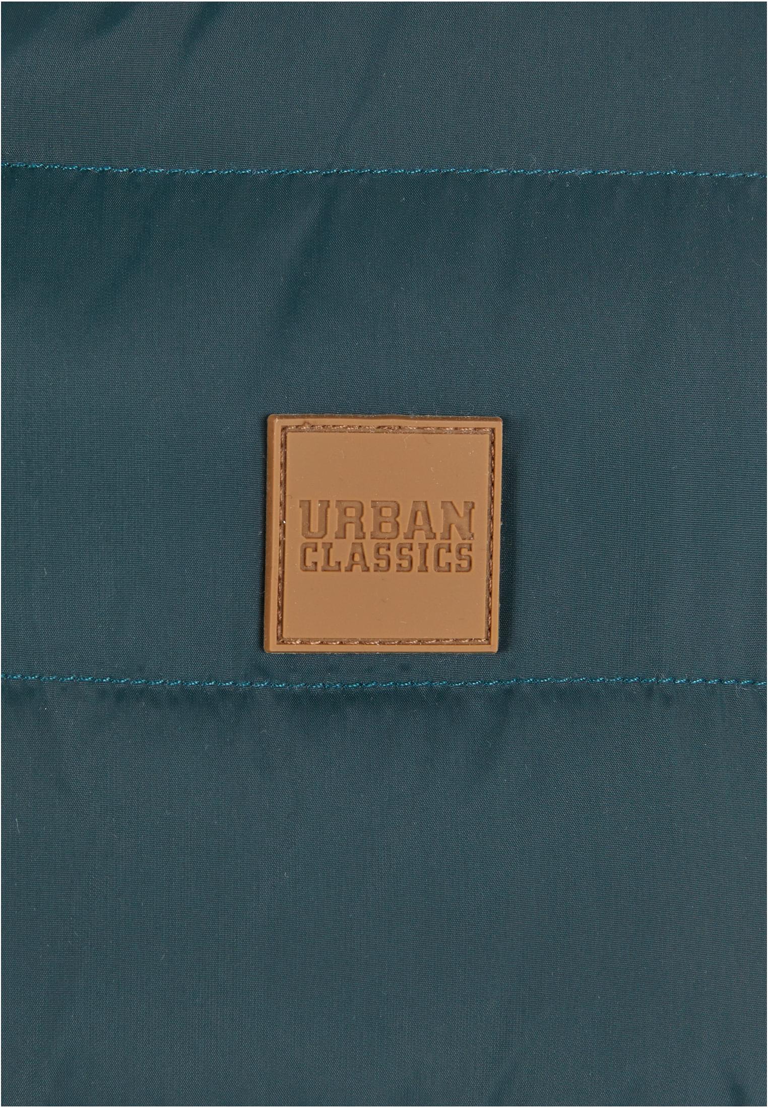 Närbild på Urban Classics-logotypen på en mörkgrön vadderad jacka.
