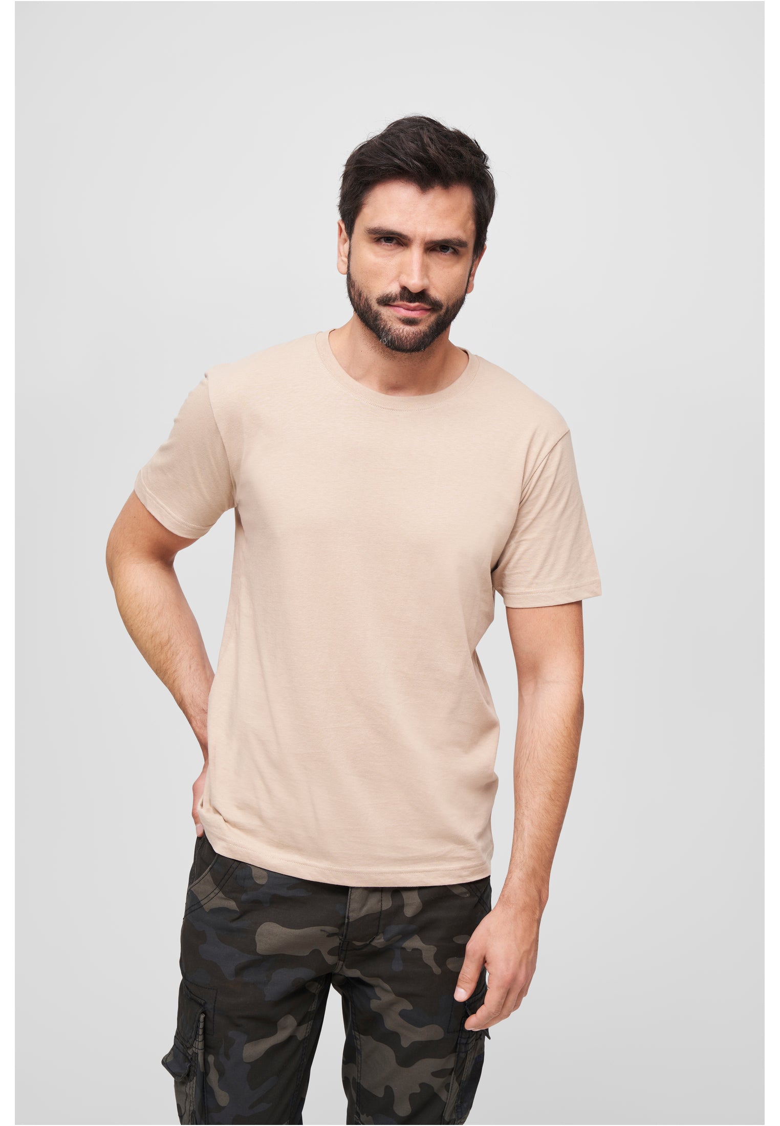 En manlig modell som bär en beige Brandit Premium Shirt och kamouflagebyxor.