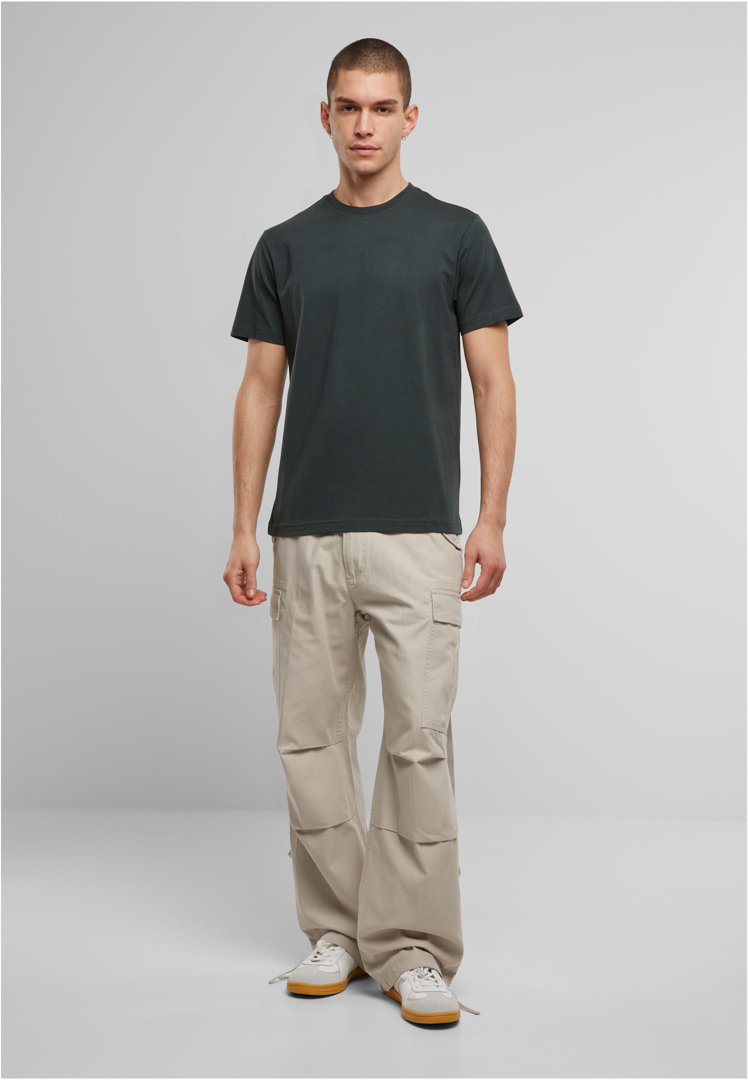 Manlig modell som bär en buteljgrön Brandit Premium t-shirt och ljusa cargobyxor, fotograferad framifrån.