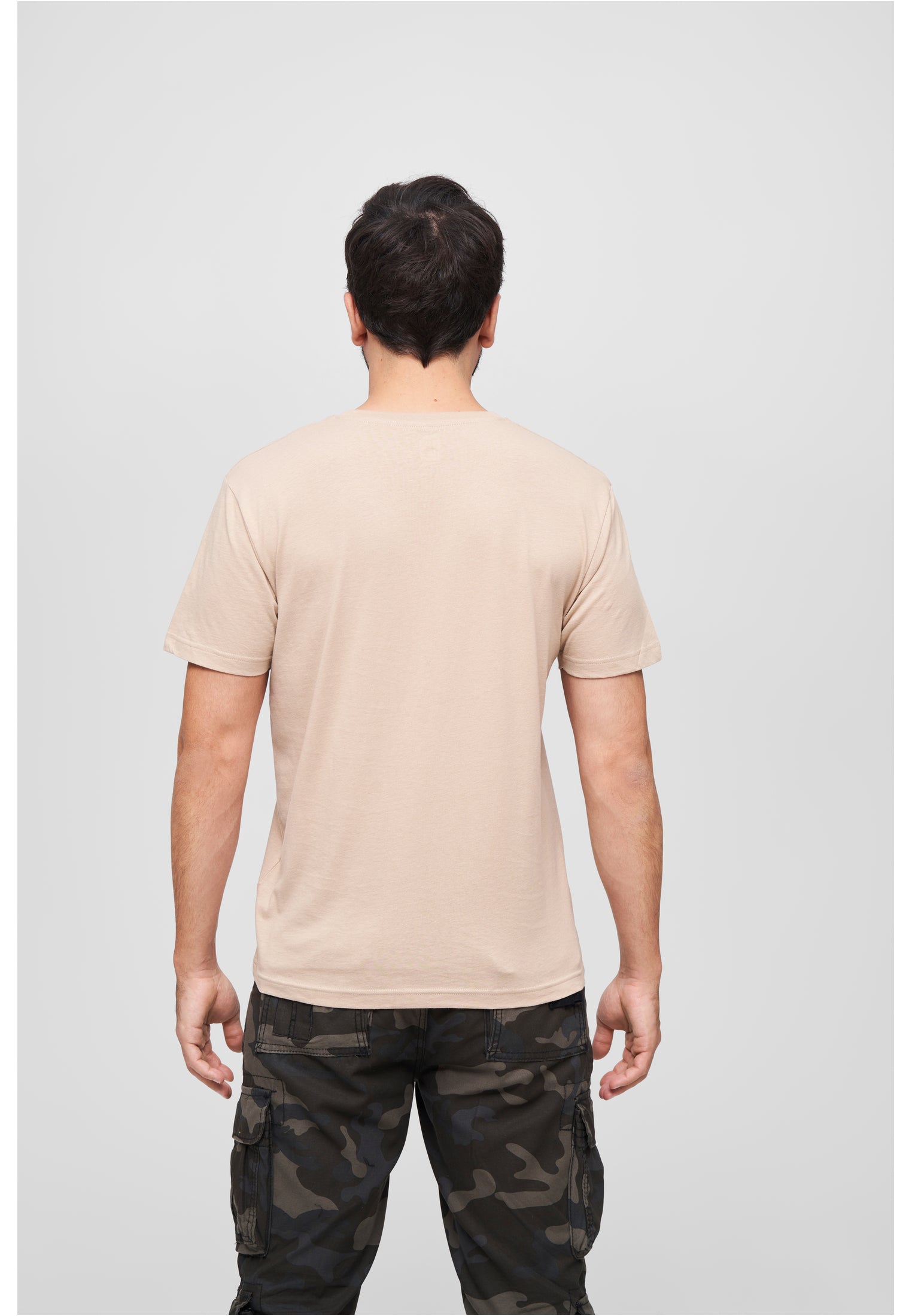 Ryggvy av en man som bär en beige Brandit Premium t-shirt och kamouflagebyxor.