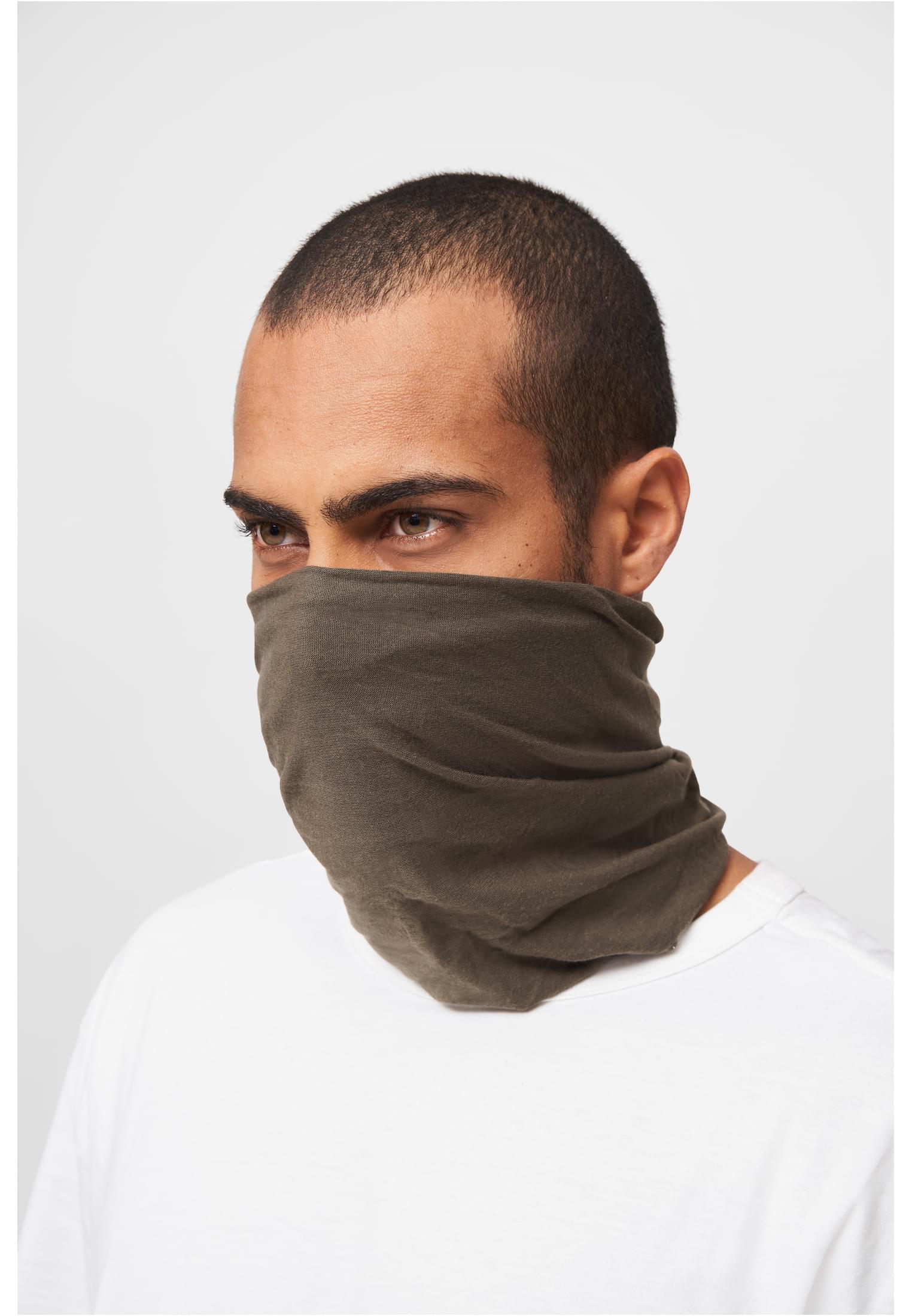 En man bär en olivgrön fleecehalsduk uppdragen över näsan och munnen mot en vit bakgrund.
