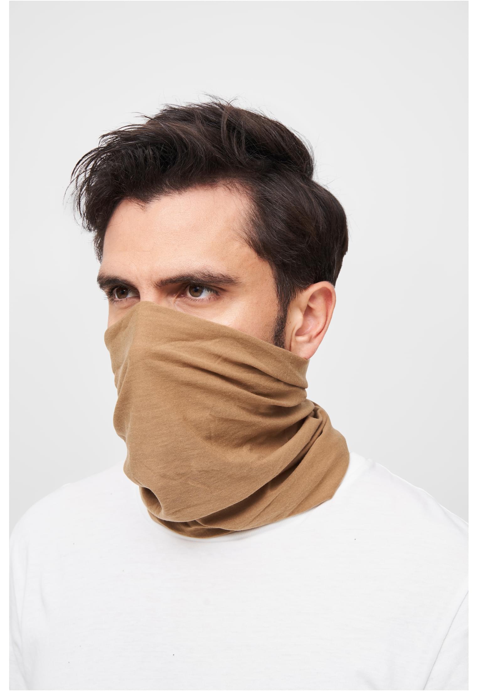 Närbild på en man som bär en beige loophalsduk uppdragen över mun och näsa.