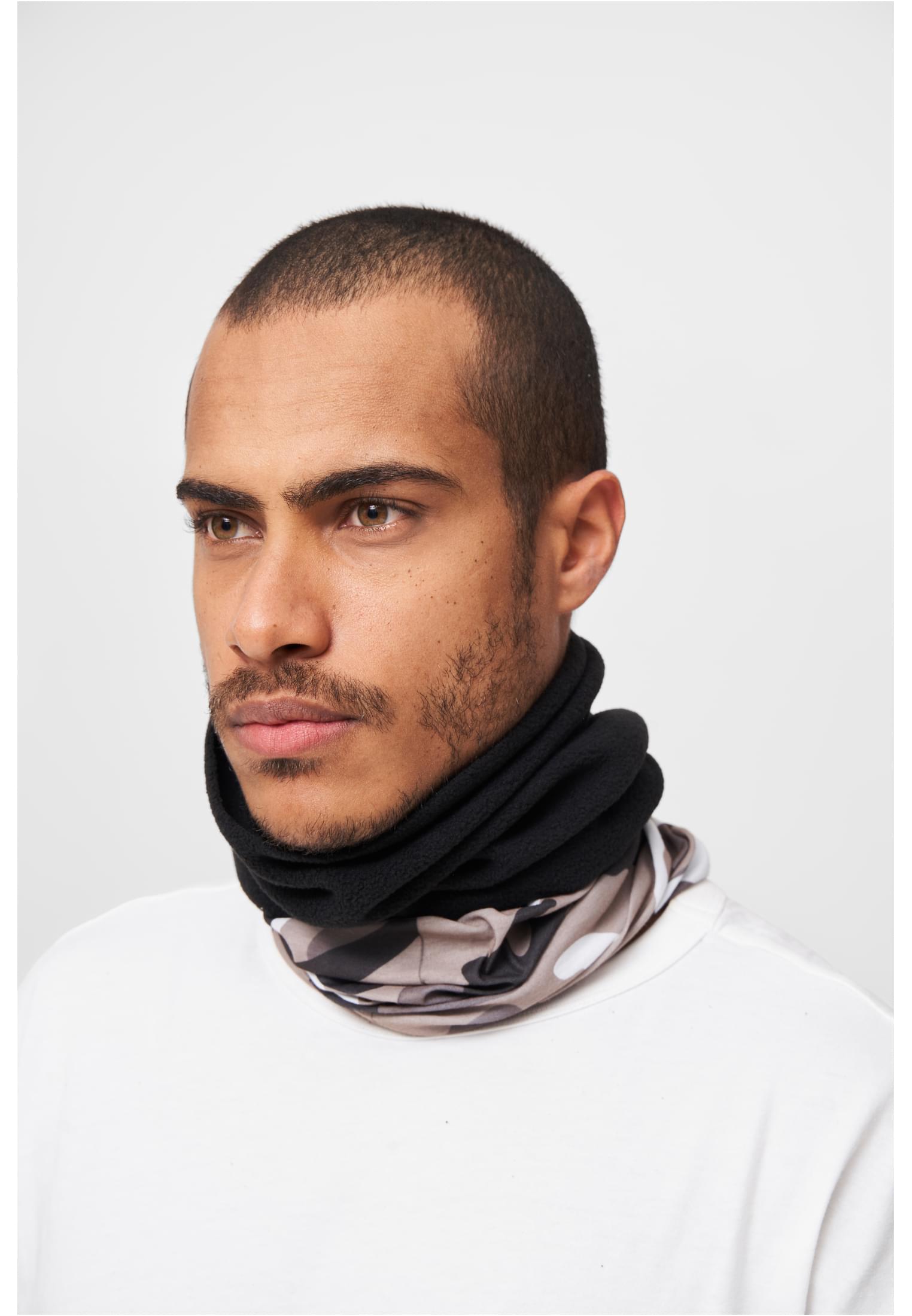 Närbild på en man som bär en B Halsduk Fleece i svart och beige kamouflage.