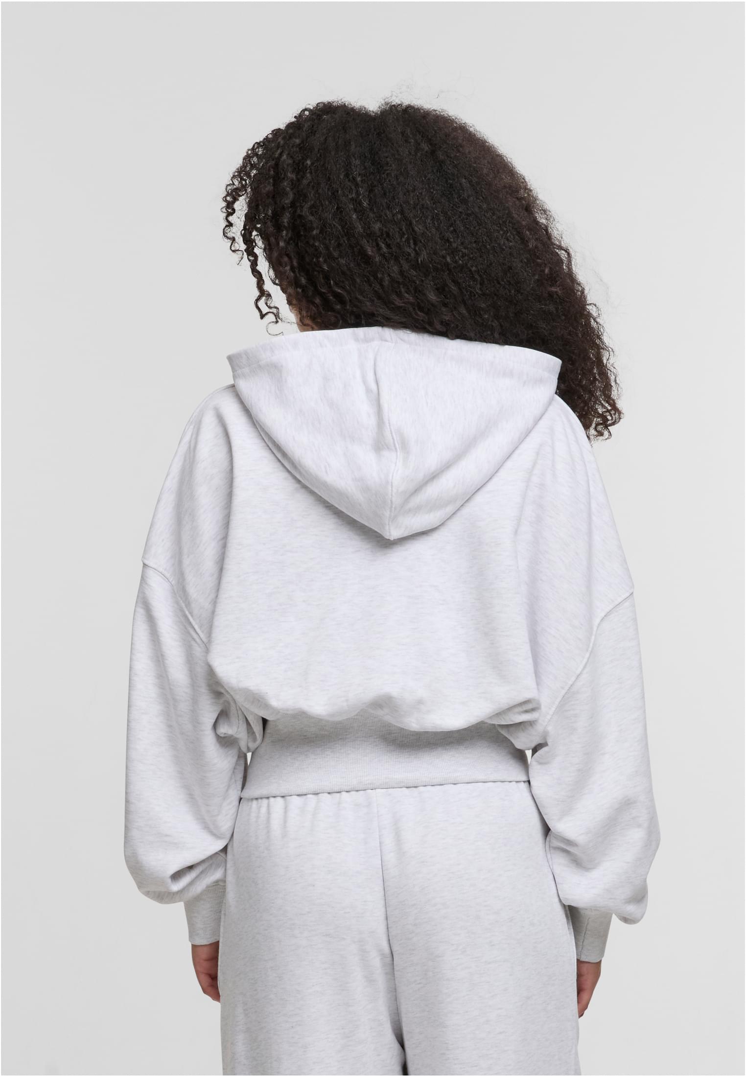 En kvinna, fotograferad bakifrån, bär en ljusgråmelerad DEF NICE Hoodie.