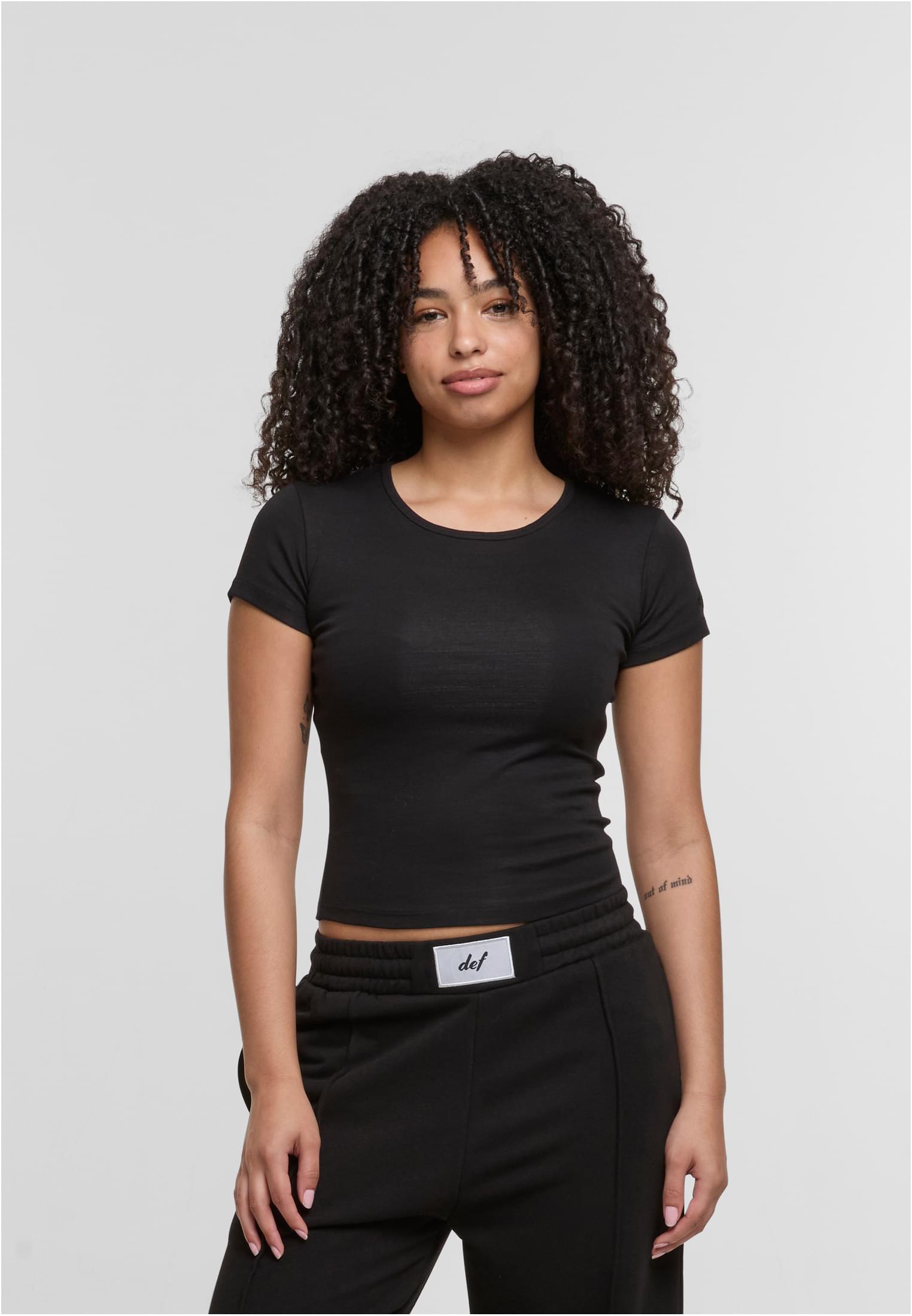 En kvinna visar framsidan av den svarta DEF Relax T-shirten.