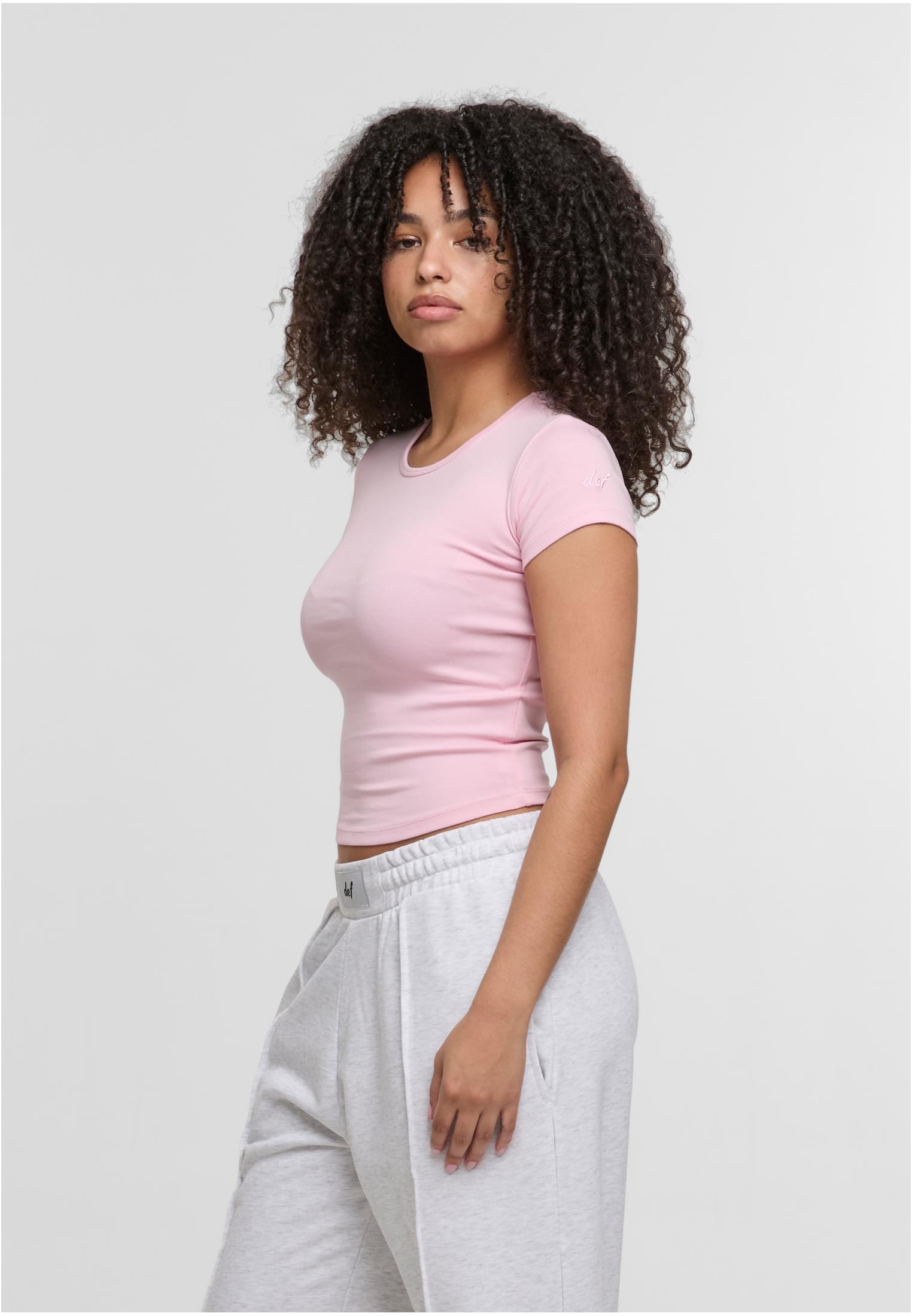 En kvinna visar upp en rosa DEF Relax T-shirt från sidan.