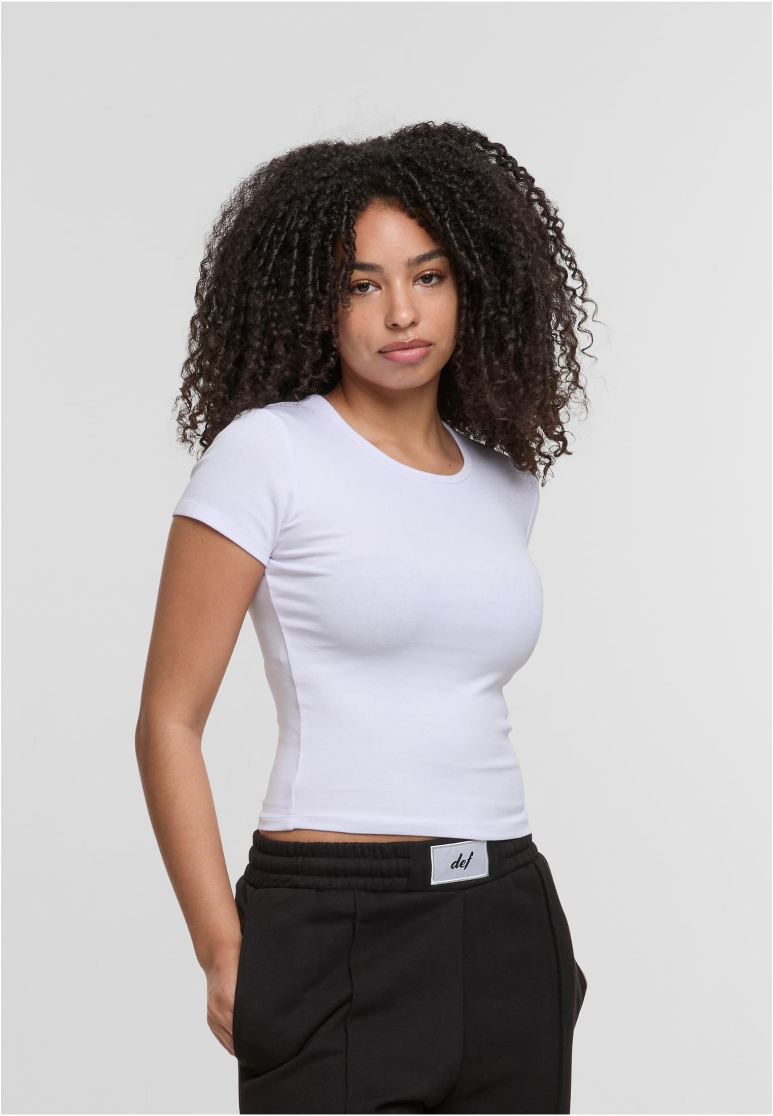 En kvinna visar framsidan av den vita DEF Relax T-shirten.