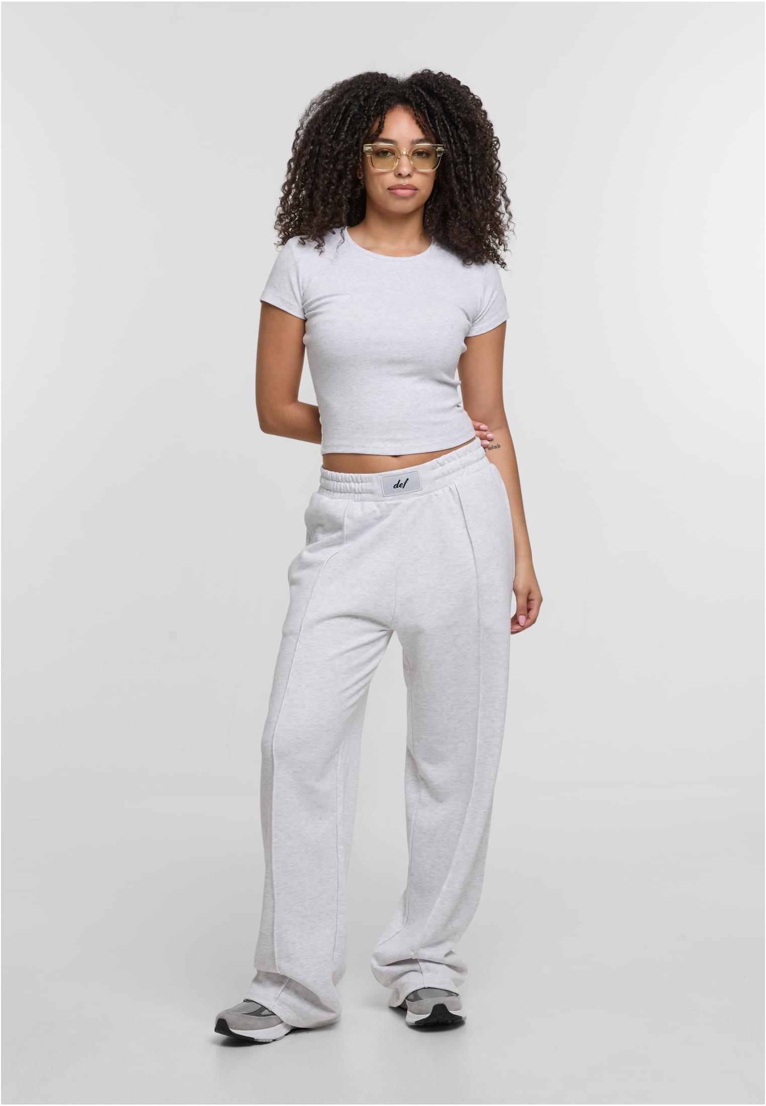 En kvinna bär en ljusgrå, kort DEF Relax T-shirt och matchande mjukisbyxor.