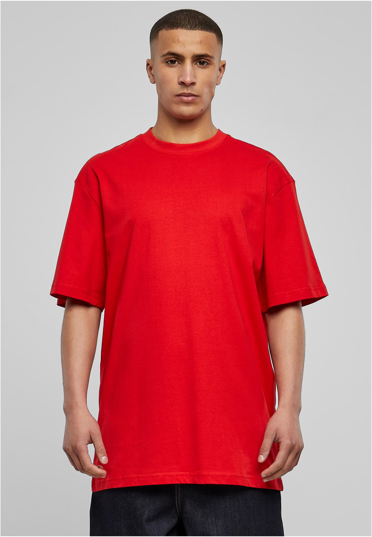 En manlig modell som bär en röd Tall Tee framifrån mot en grå bakgrund.