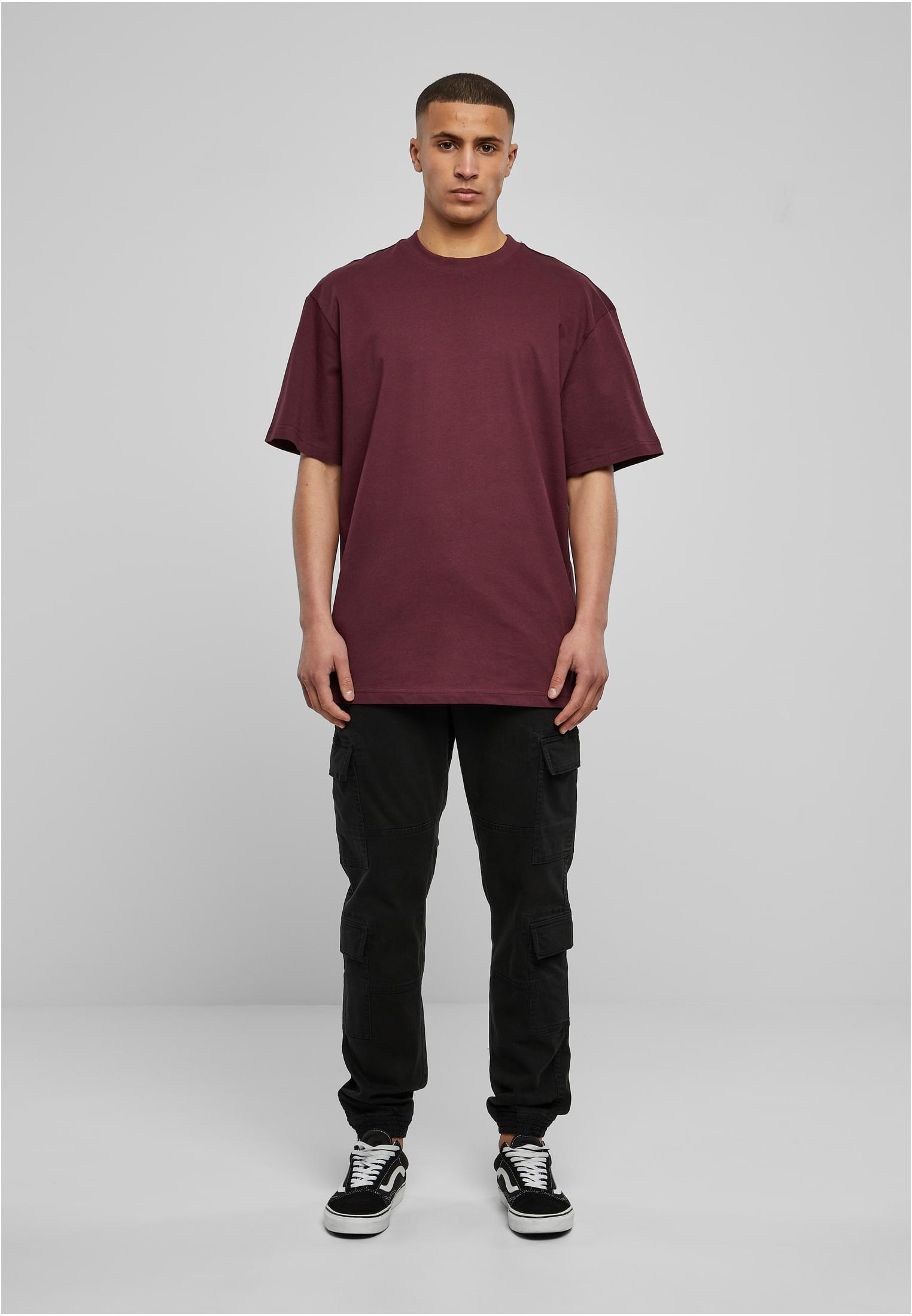 Manlig modell som bär en vinröd Tall Tee med extra lång passform, svarta cargobyxor och sneakers.