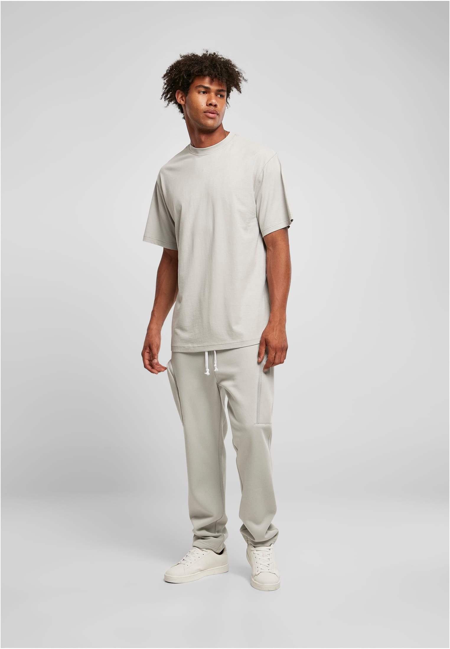 En manlig modell bär en frostmintfärgad Tall Tee med extra lång passform, matchande mjukisbyxor och vita sneakers mot en ljusgrå bakgrund.