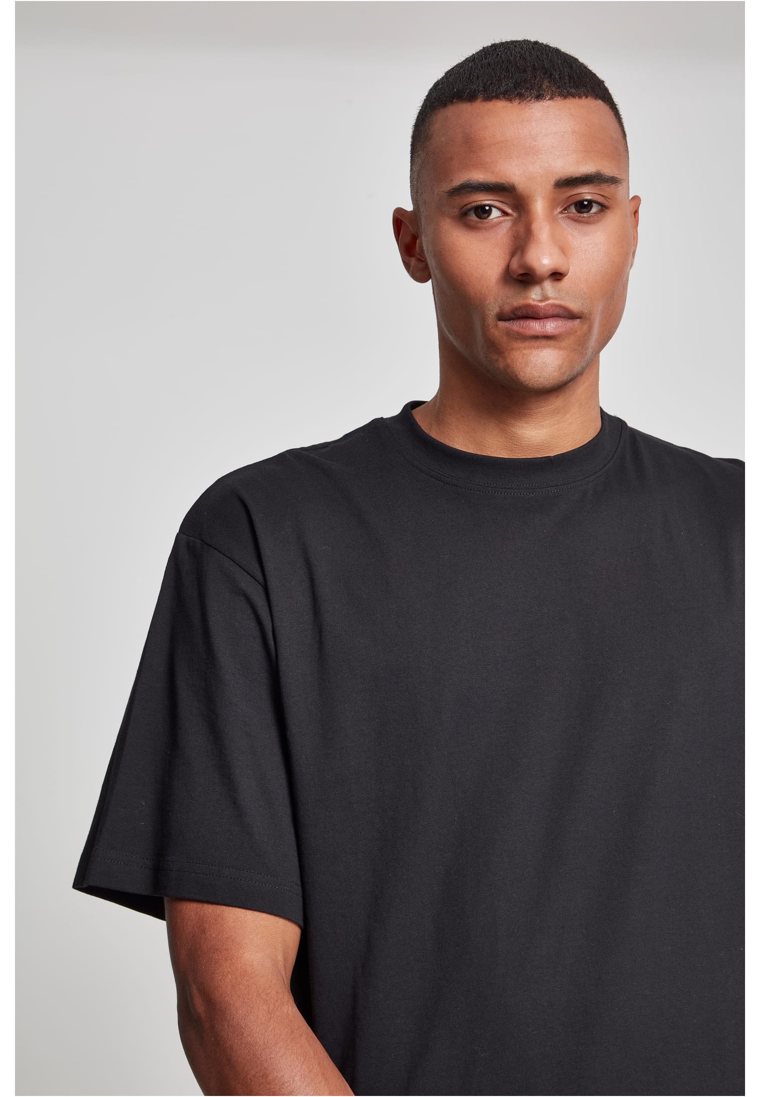 Närbild på en man som bär en svart Tall Tee från Urban Classics.