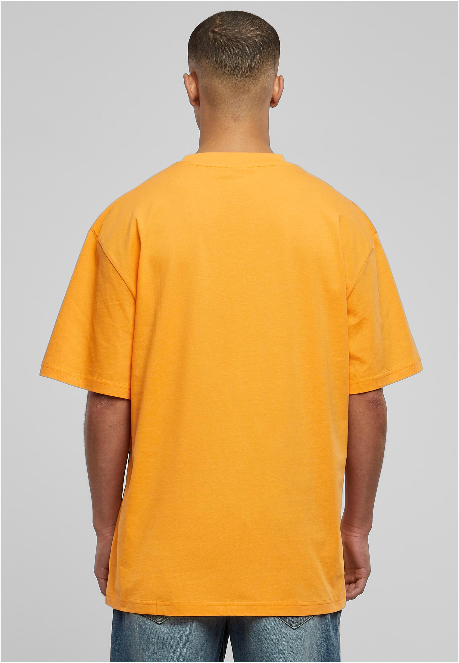 Man sedd bakifrån som bär en orange oversized Tall Tee från Urban Classics.