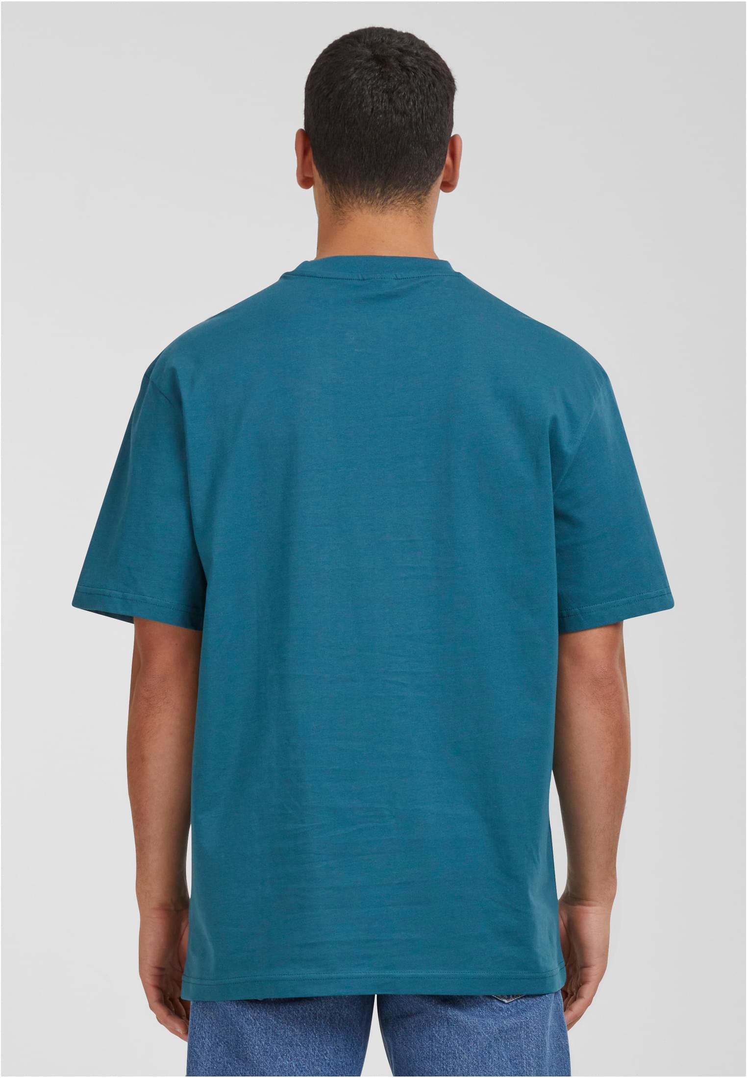 En man sedd bakifrån, bärandes en mintgrön Tall Tee med extra lång passform.