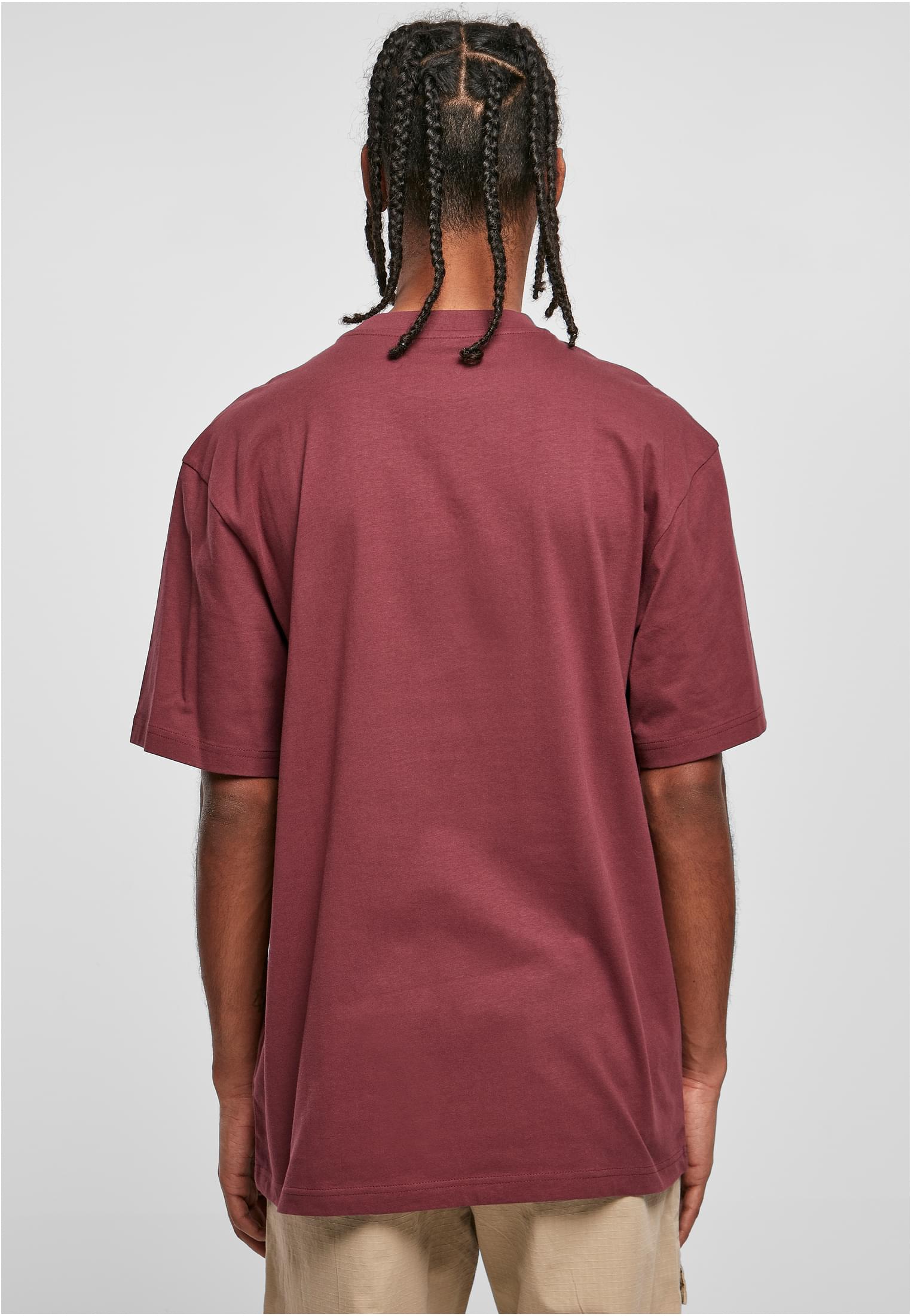 Manlig modell med flätor sedd bakifrån, klädd i en vinröd Tall Tee.