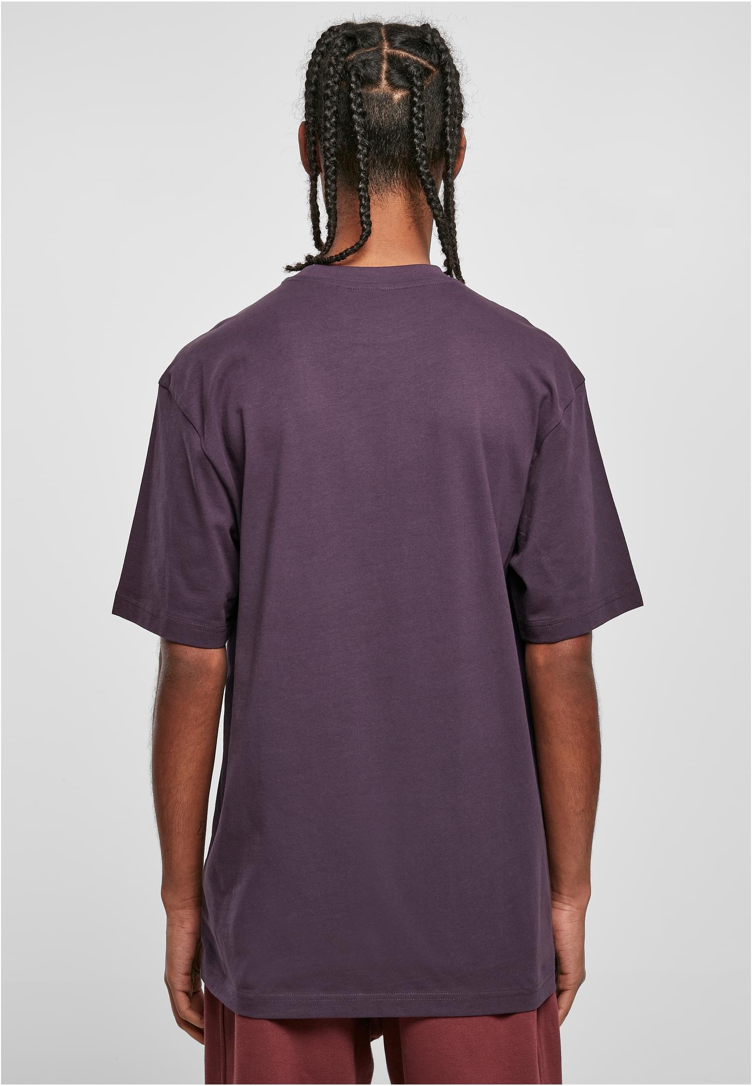 En man med ryggen mot kameran, klädd i en mörklila Tall Tee med en lång, avslappnad passform.