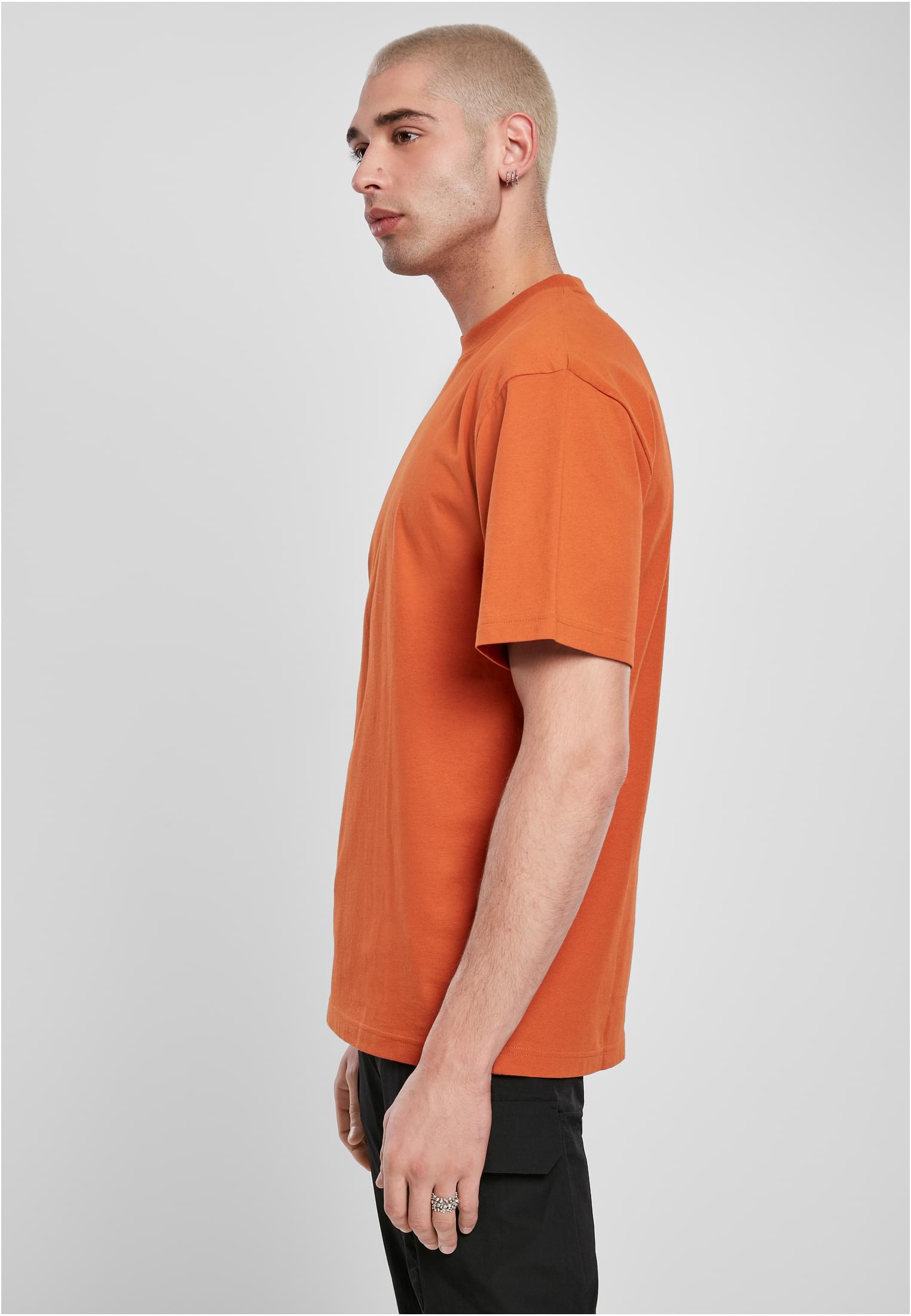 Man med kort, ljust hår fotograferad från sidan, klädd i en orange t-shirt av modellen Tall Tee.