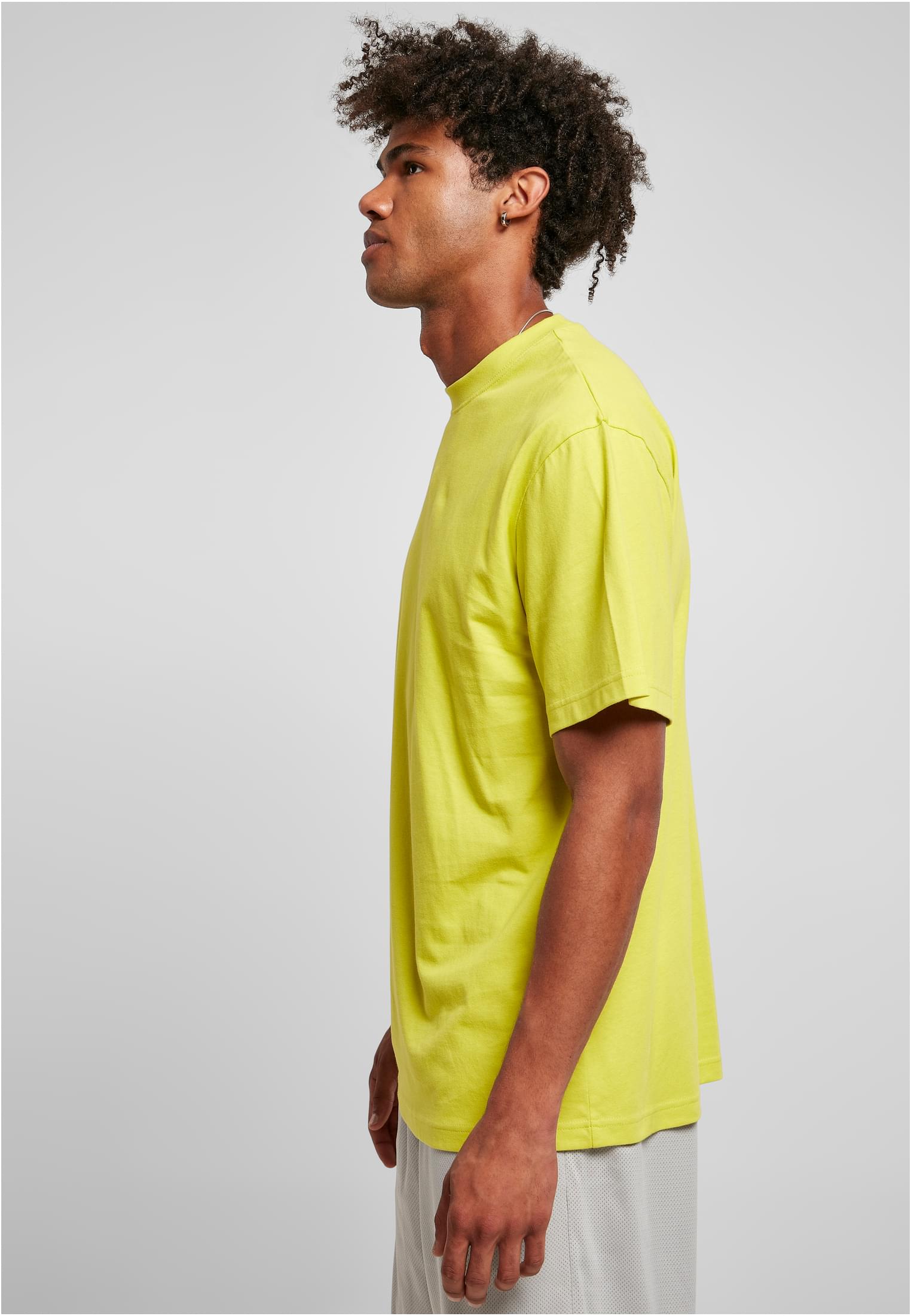 Man i sidoprofil som bär en ljusgrön, extra lång t-shirt från Urban Classics.