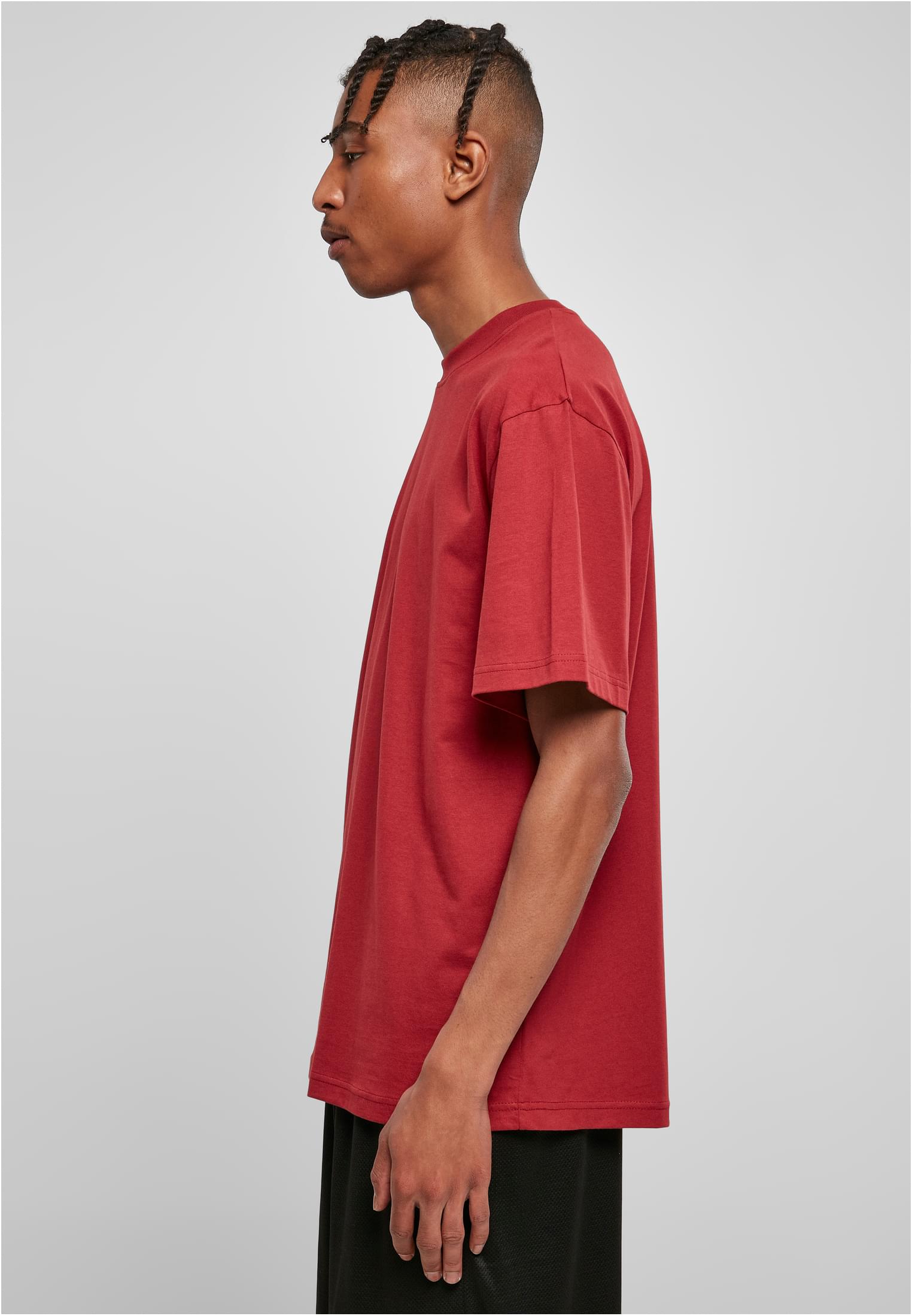 Manlig modell i profil som bär en röd Tall Tee från Urban Classics.