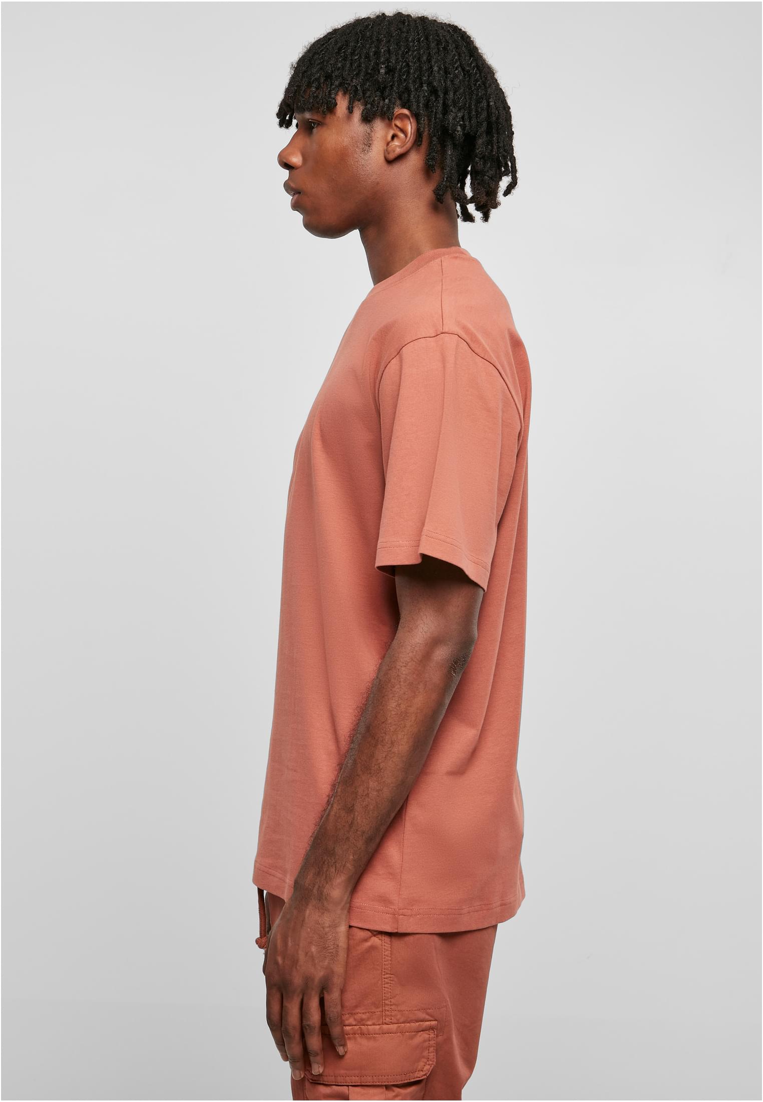 En man, sedd från sidan, som bär en rostfärgad Tall Tee t-shirt mot en ljusgrå bakgrund.