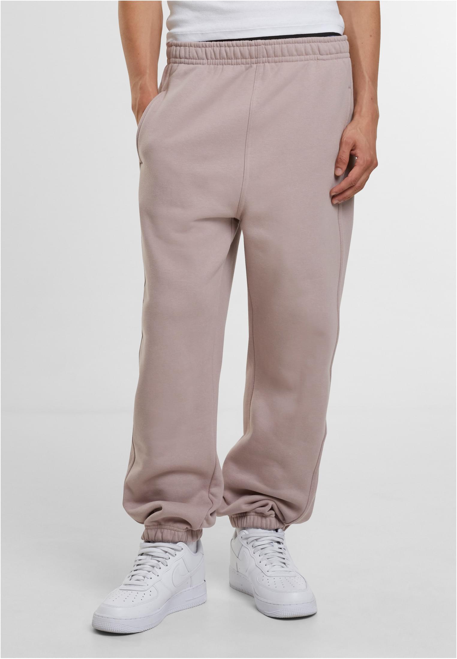 En man som bär sandfärgade UC Sweatpants och vita sneakers.