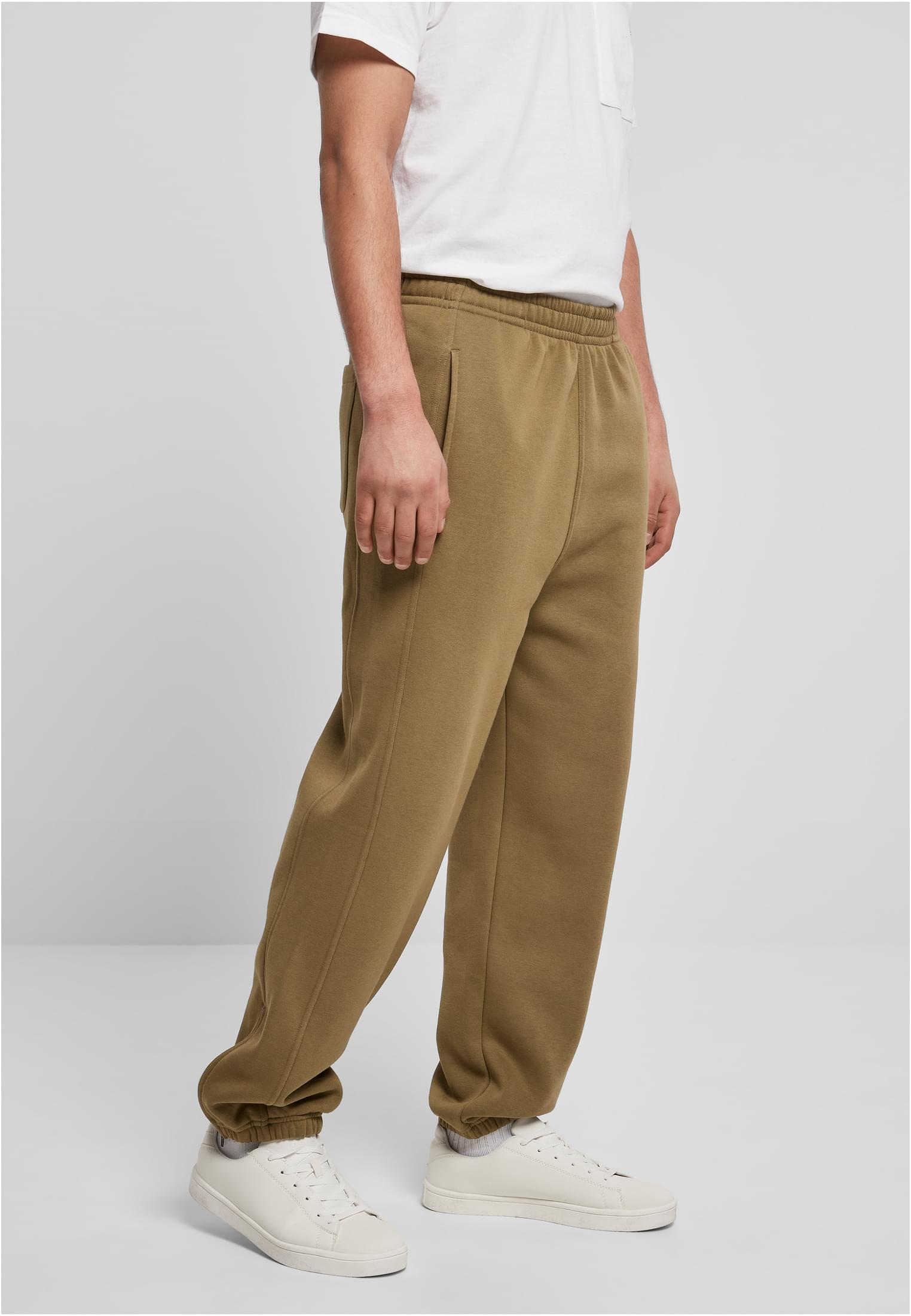 Sidovy av en man som bär ett par brungröna UC Sweatpants med en vit t-shirt och vita sneakers.