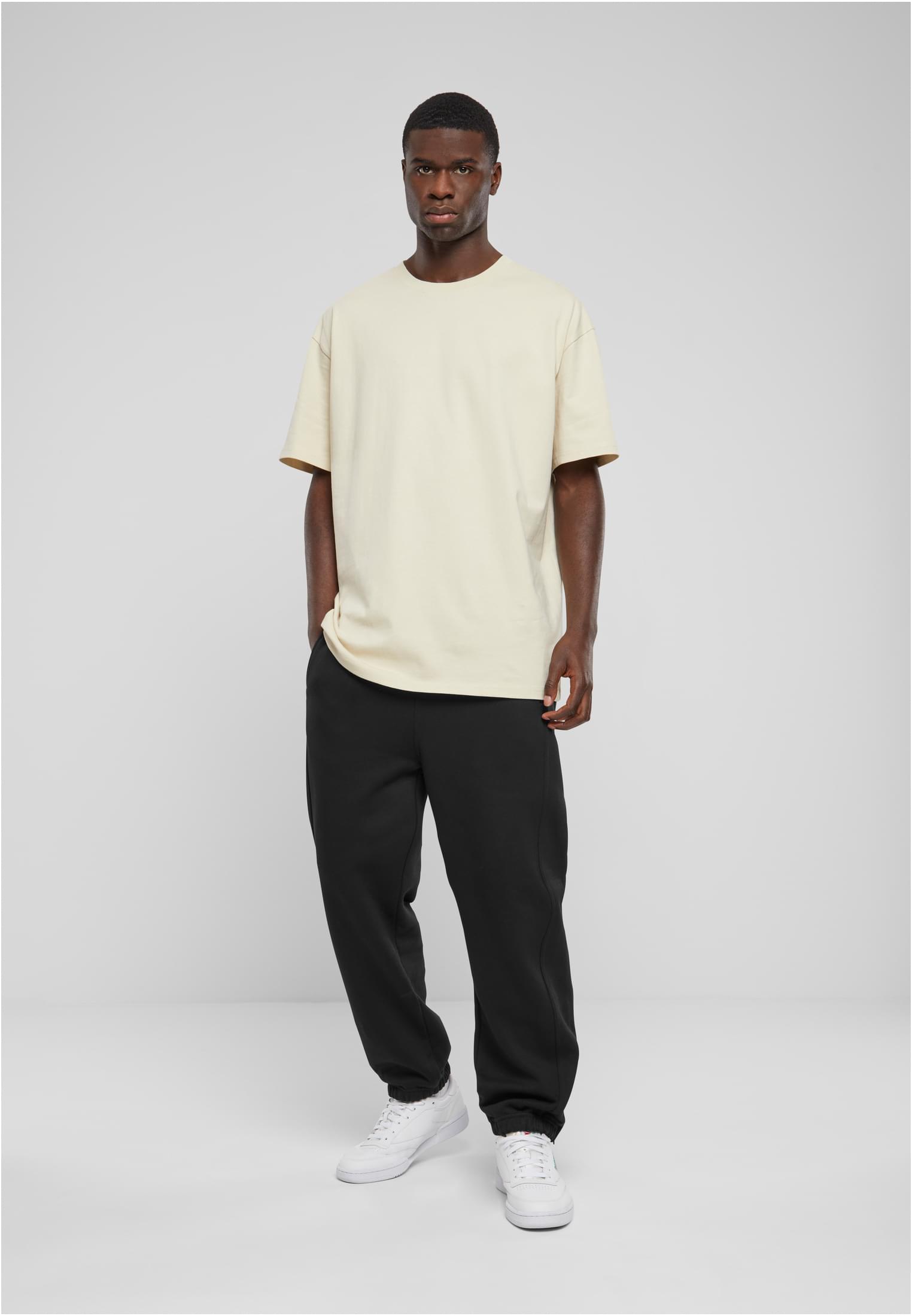 Man som bär svarta UC Sweatpants, en ljus t-shirt och vita sneakers.