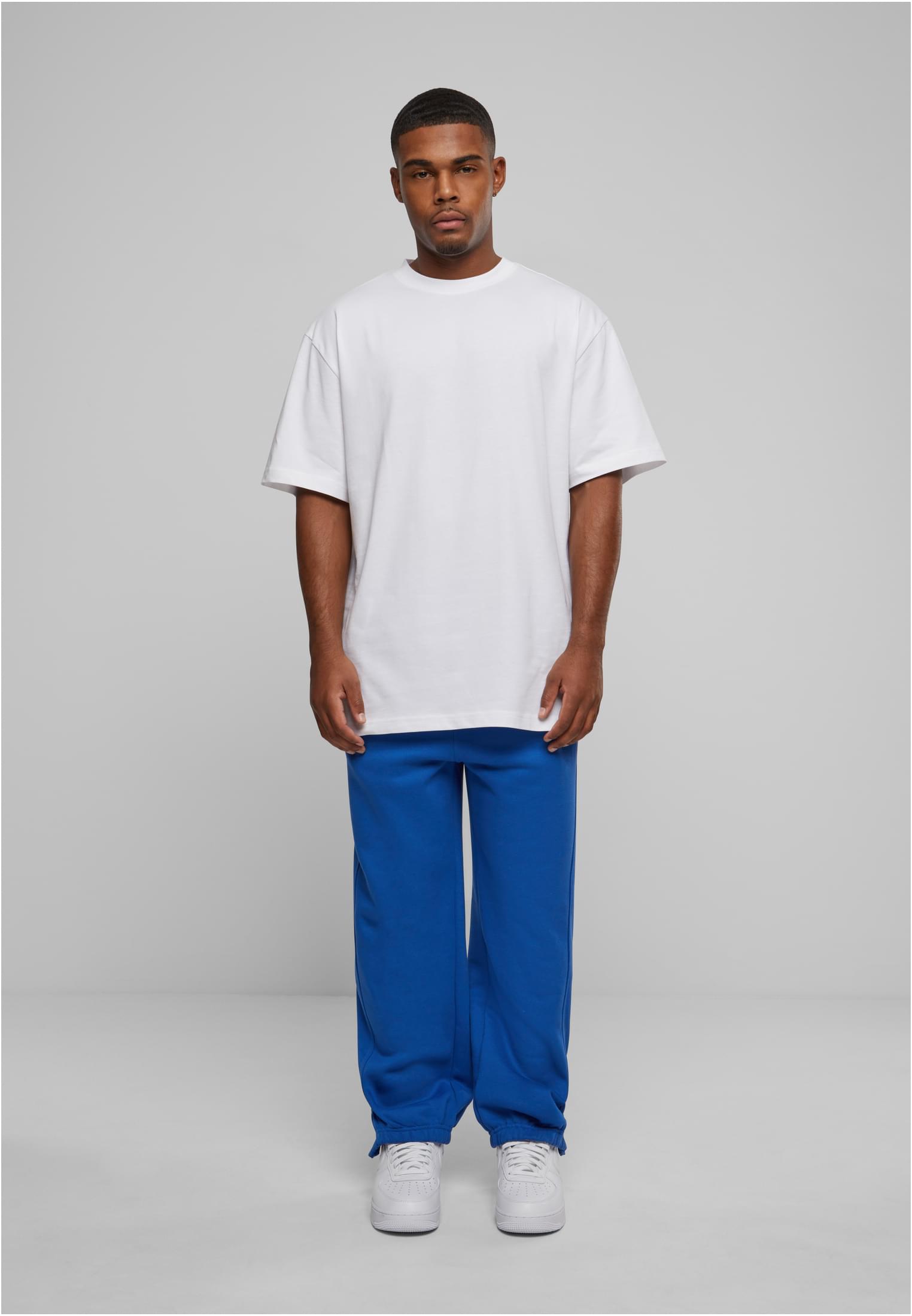 En manlig modell som bär blåa UC Sweatpants och en vit T-shirt.