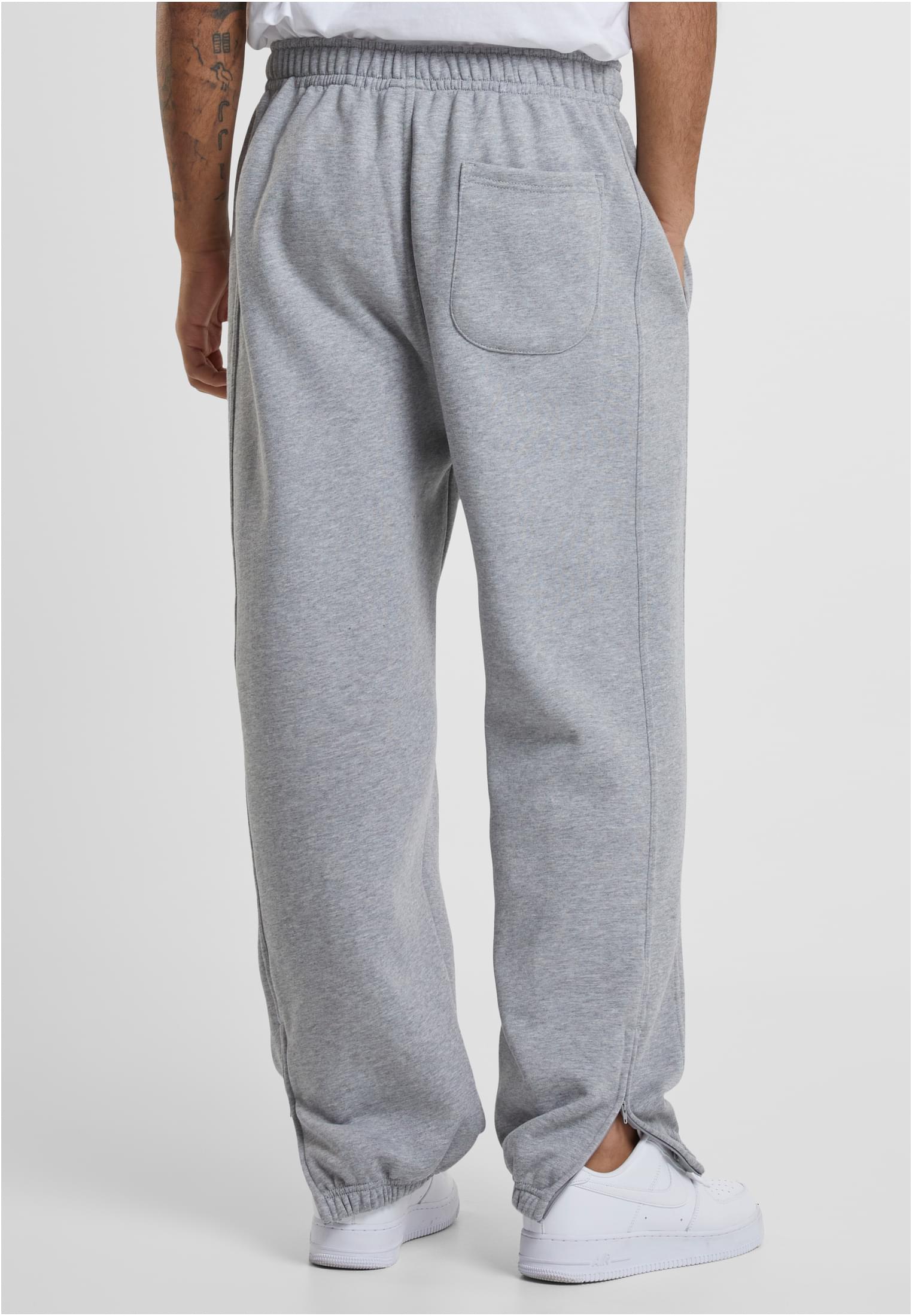 Man sedd bakifrån i gråa sweatpants med en bakficka och dragkedja vid ankeln.